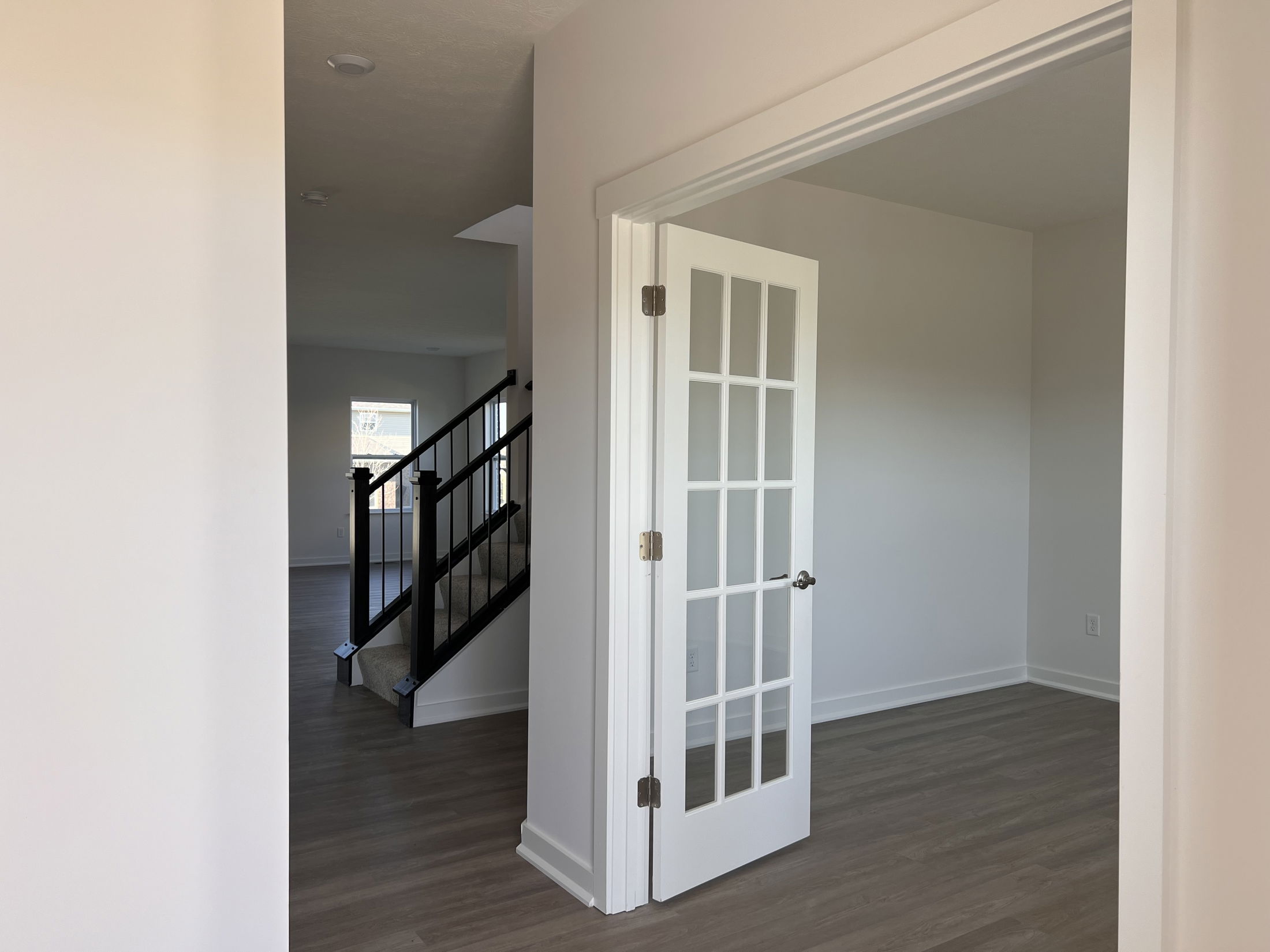 Spacious modern interior with French doors, wooden flooring, and a staircase leading to the upper level.