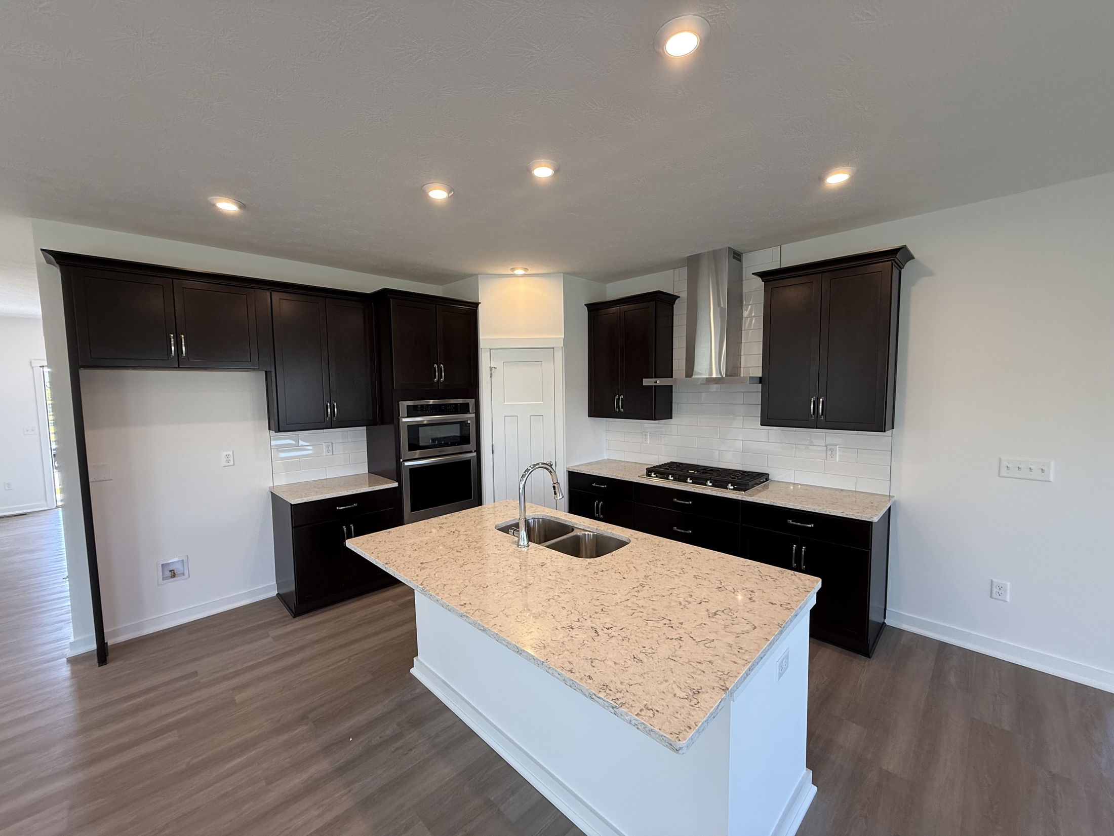 Modern kitchen interior with dark cabinets, marble countertops, and stainless steel appliances.