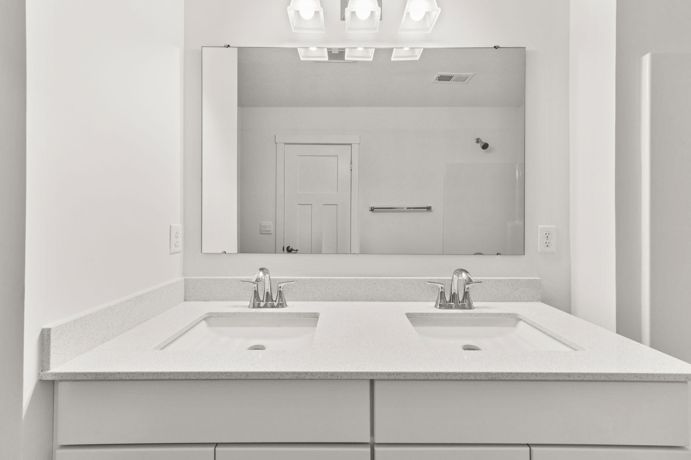 Modern white bathroom with a large mirror, double sink, and chrome faucets.