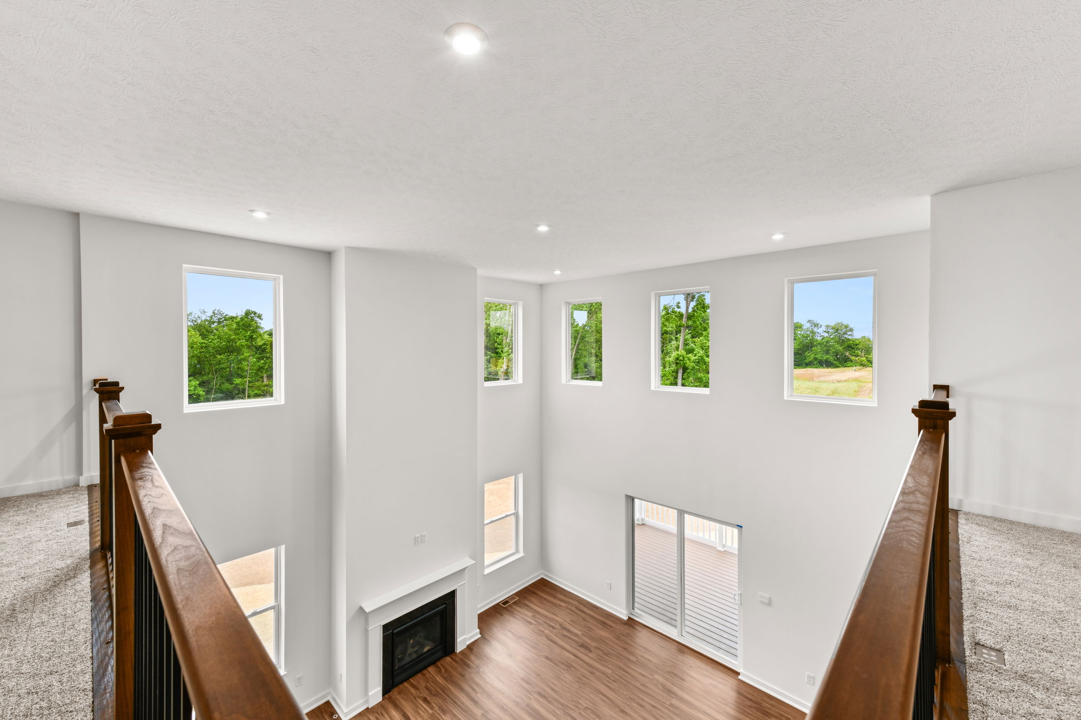 Bright, modern living room with high ceilings, large windows, wooden flooring, and a fireplace, offering a spacious and elegant interior design.