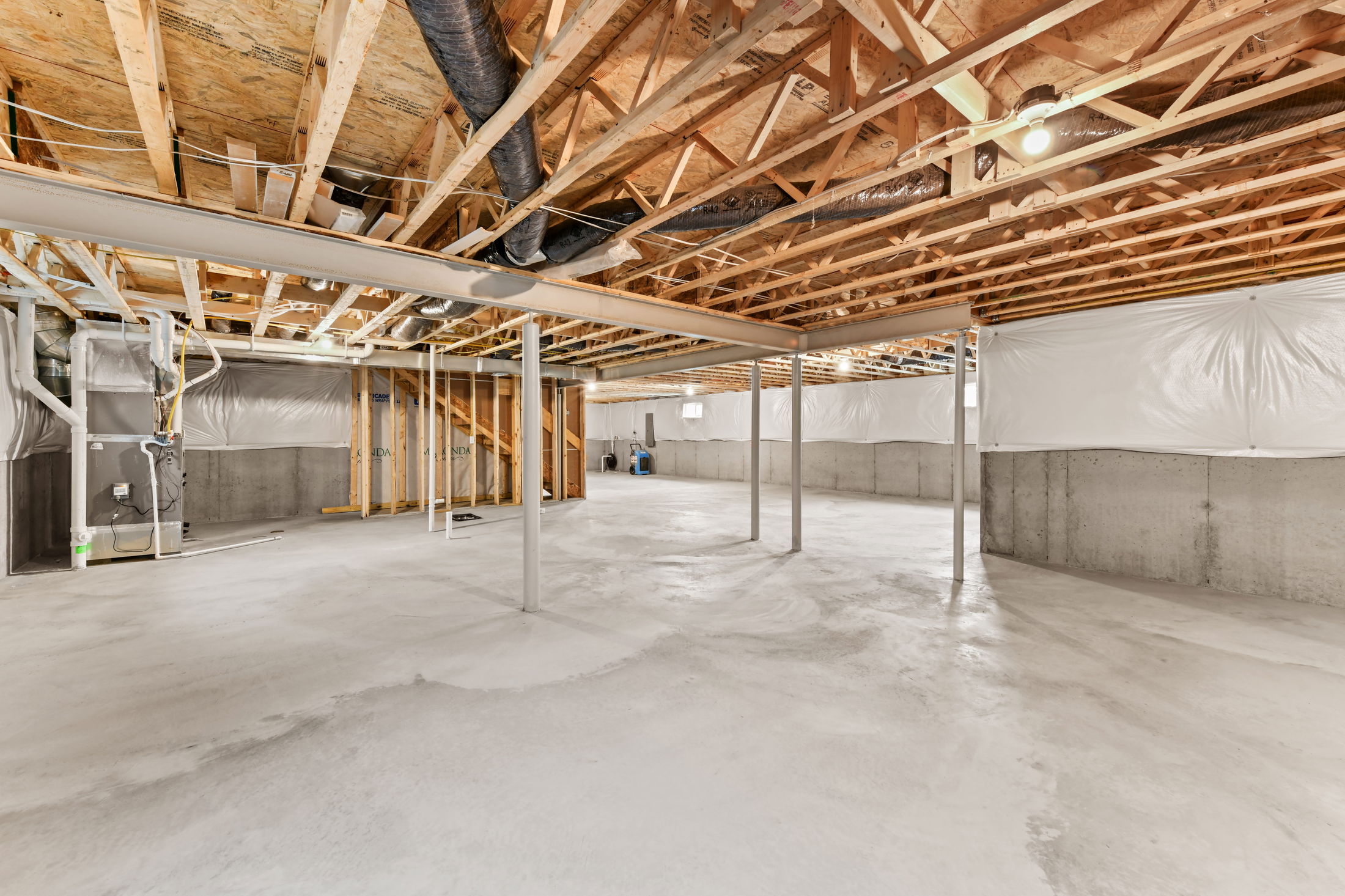 Spacious unfinished basement with exposed wooden beams, concrete floor, and visible HVAC system.