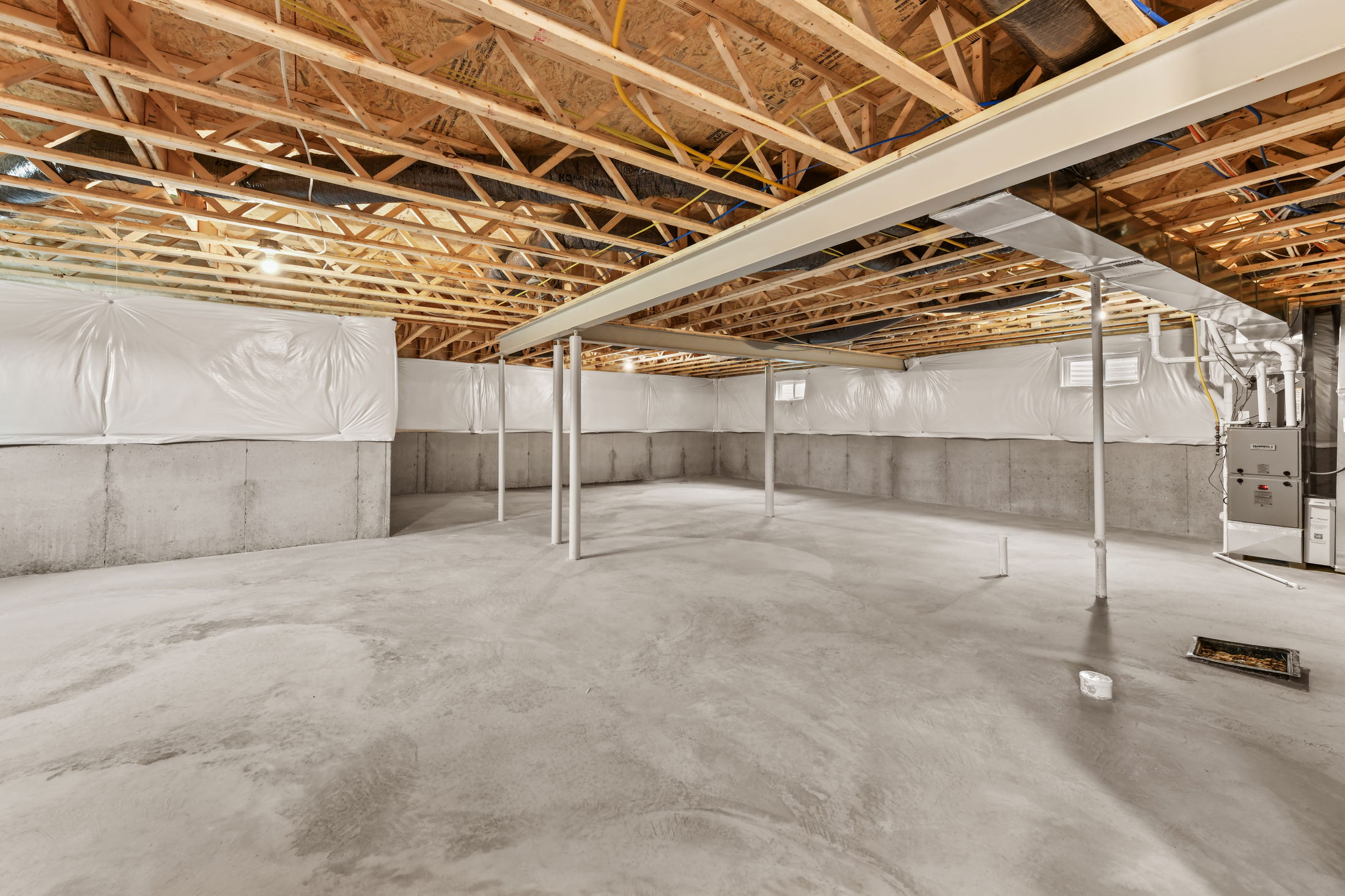 Spacious unfinished basement with exposed wooden beams and HVAC system, ideal for customization and home renovation.