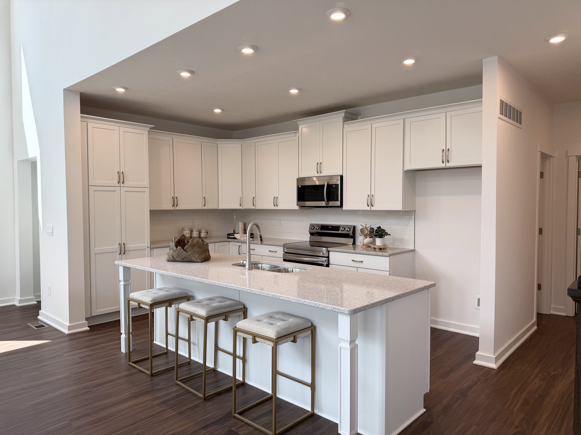 Modern kitchen with white cabinetry, stainless steel appliances, and a large island featuring bar stools.