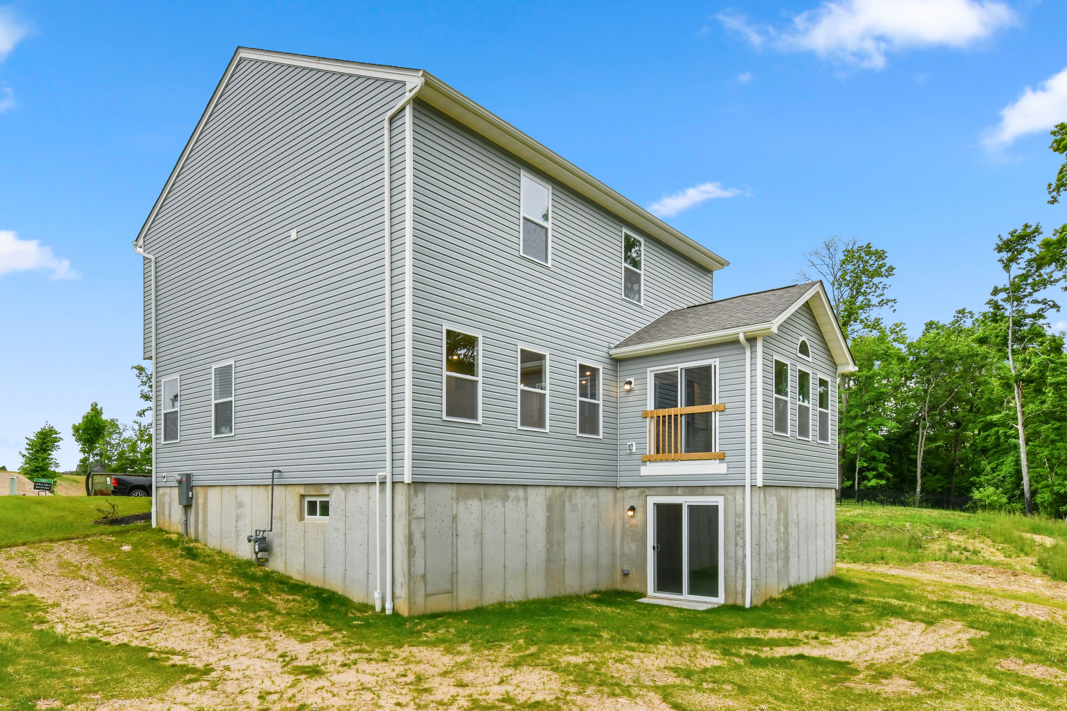 Modern two-story house with gray siding and spacious backyard on a sunny day.
