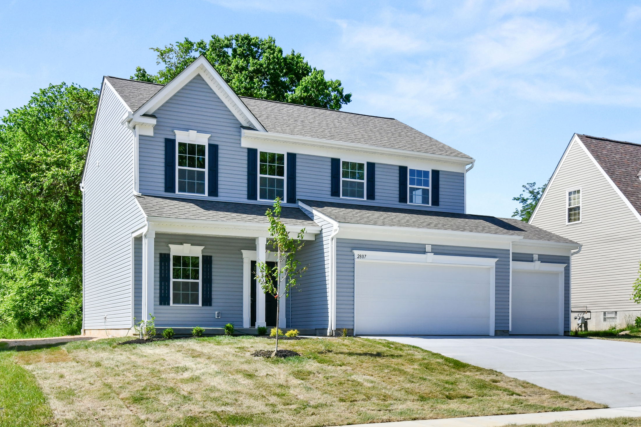 Modern two-story suburban house with a three-car garage and well-maintained lawn.