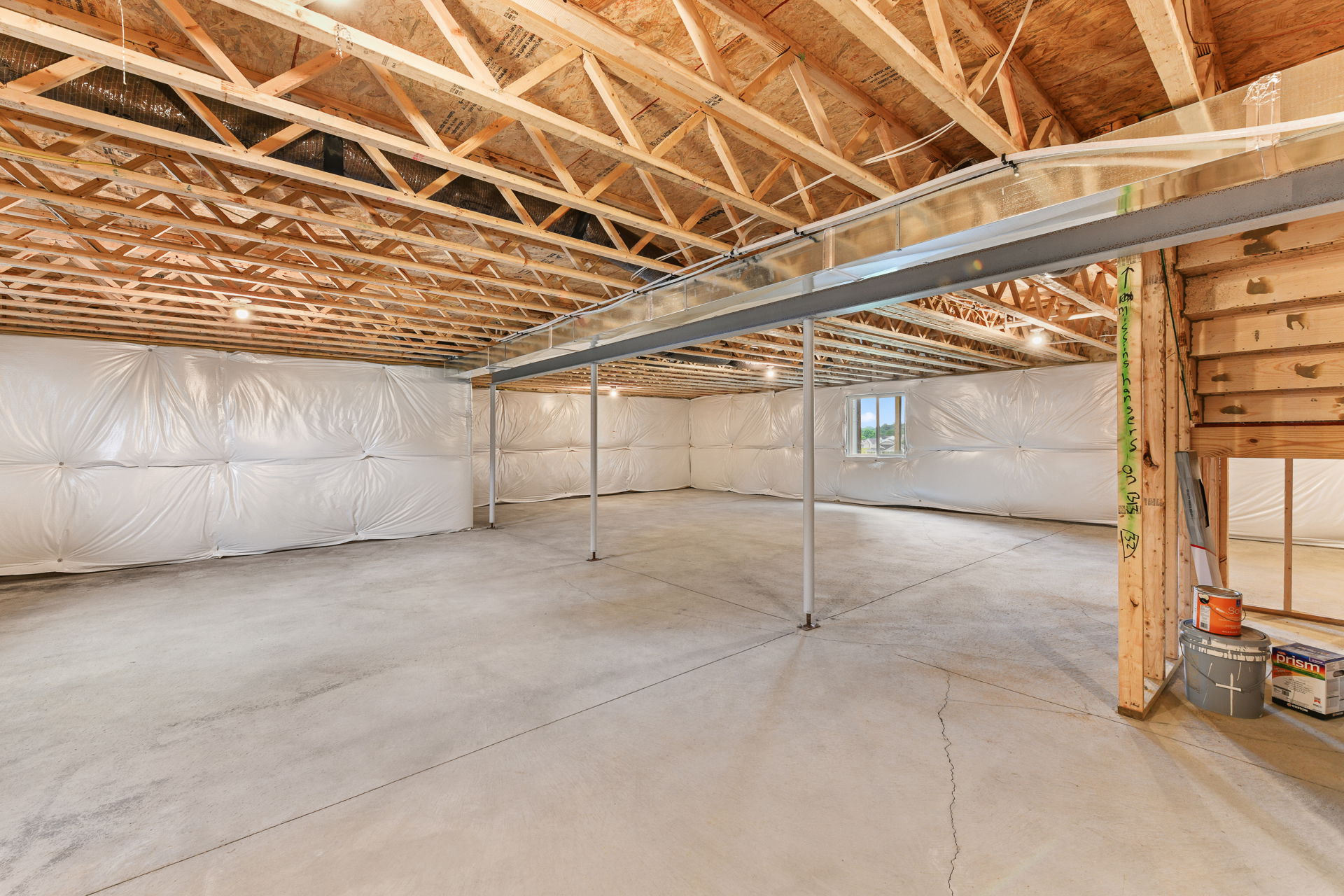 Wide open unfinished basement with exposed wooden beams and concrete floor.