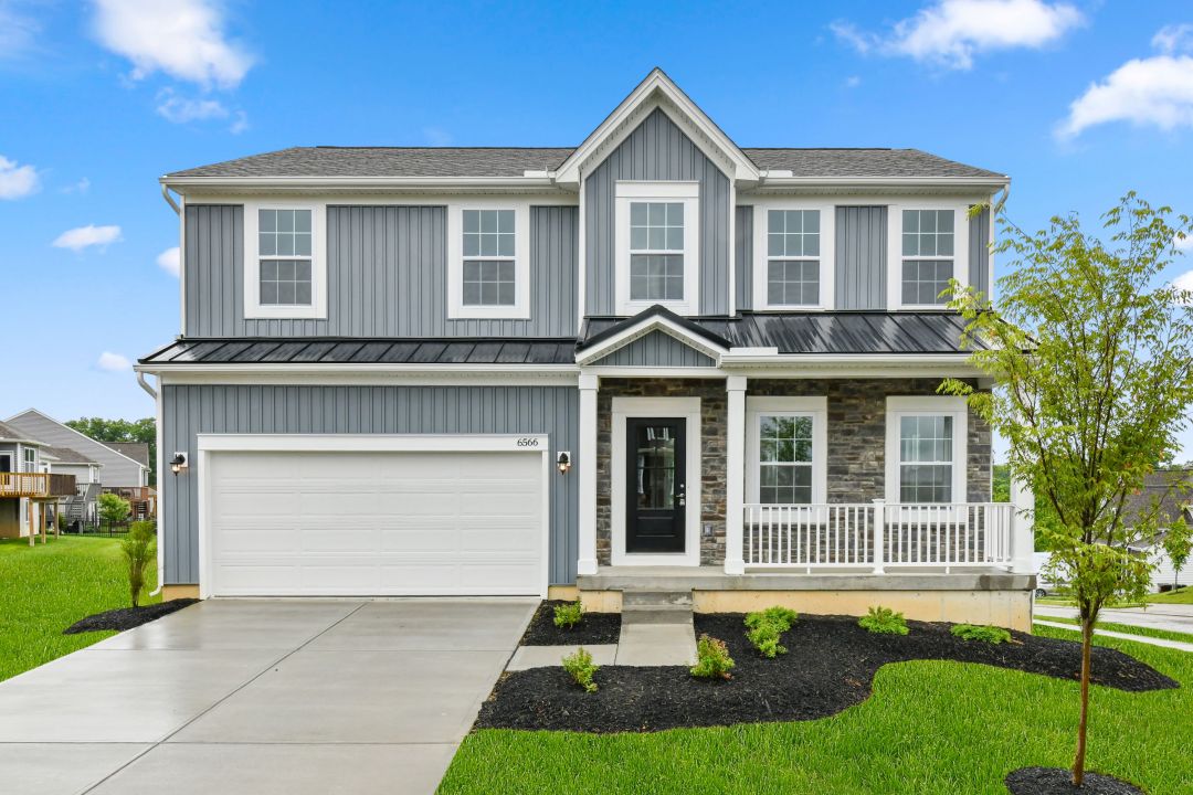Beautiful two-story gray house with white trim, a front porch, and a spacious driveway on a sunny day.
