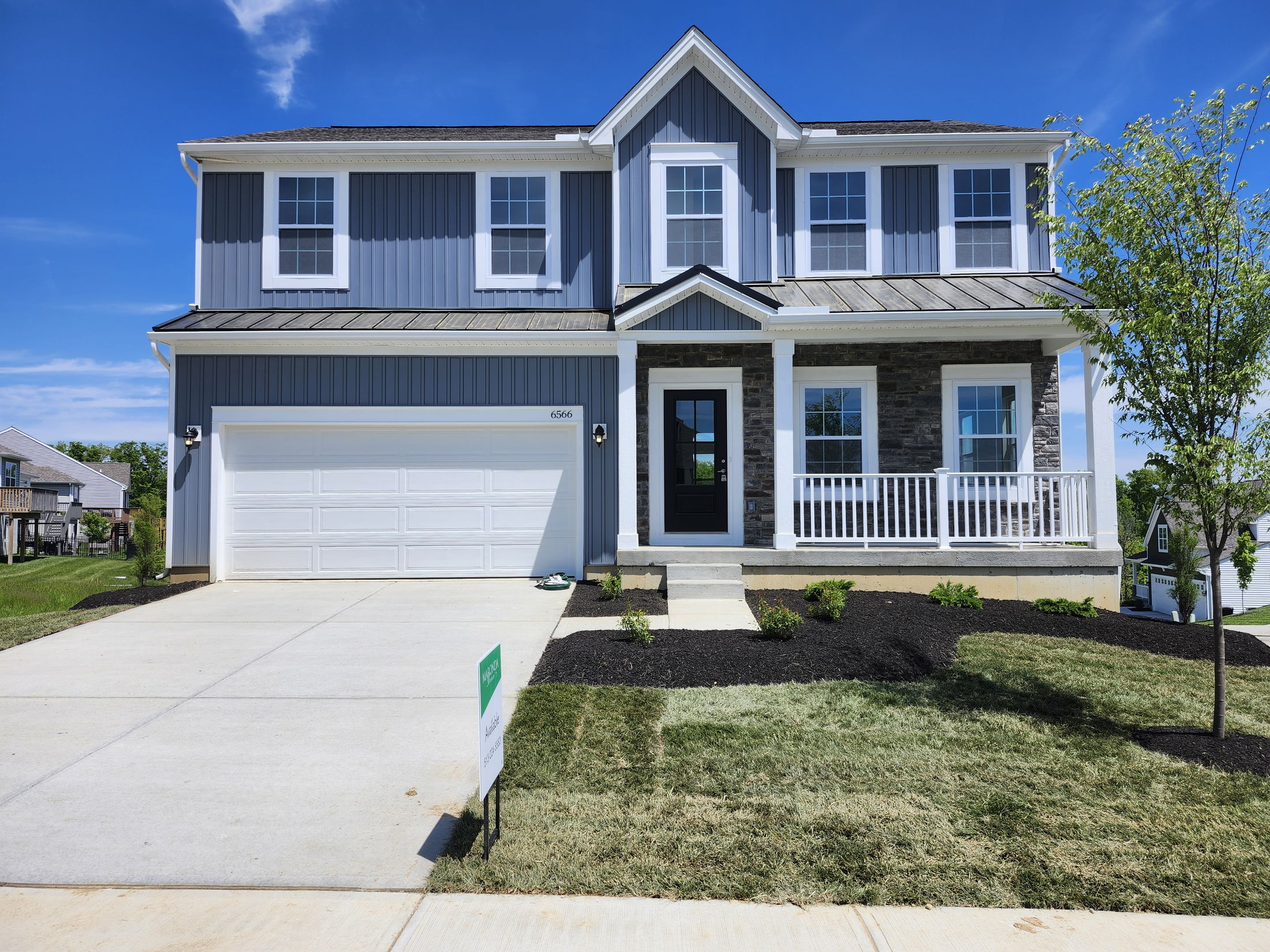 Modern two-story house with blue siding, a two-car garage, and a neatly landscaped front yard.