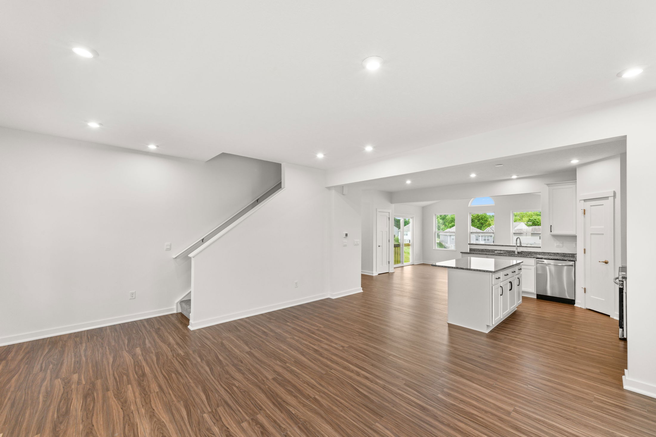 Modern open-concept kitchen and living area with elegant wooden floors and white cabinetry.