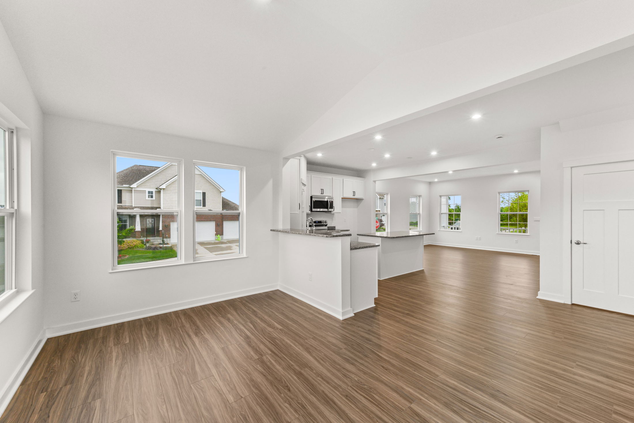 Spacious, modern open-plan kitchen and living area with large windows and hardwood flooring.