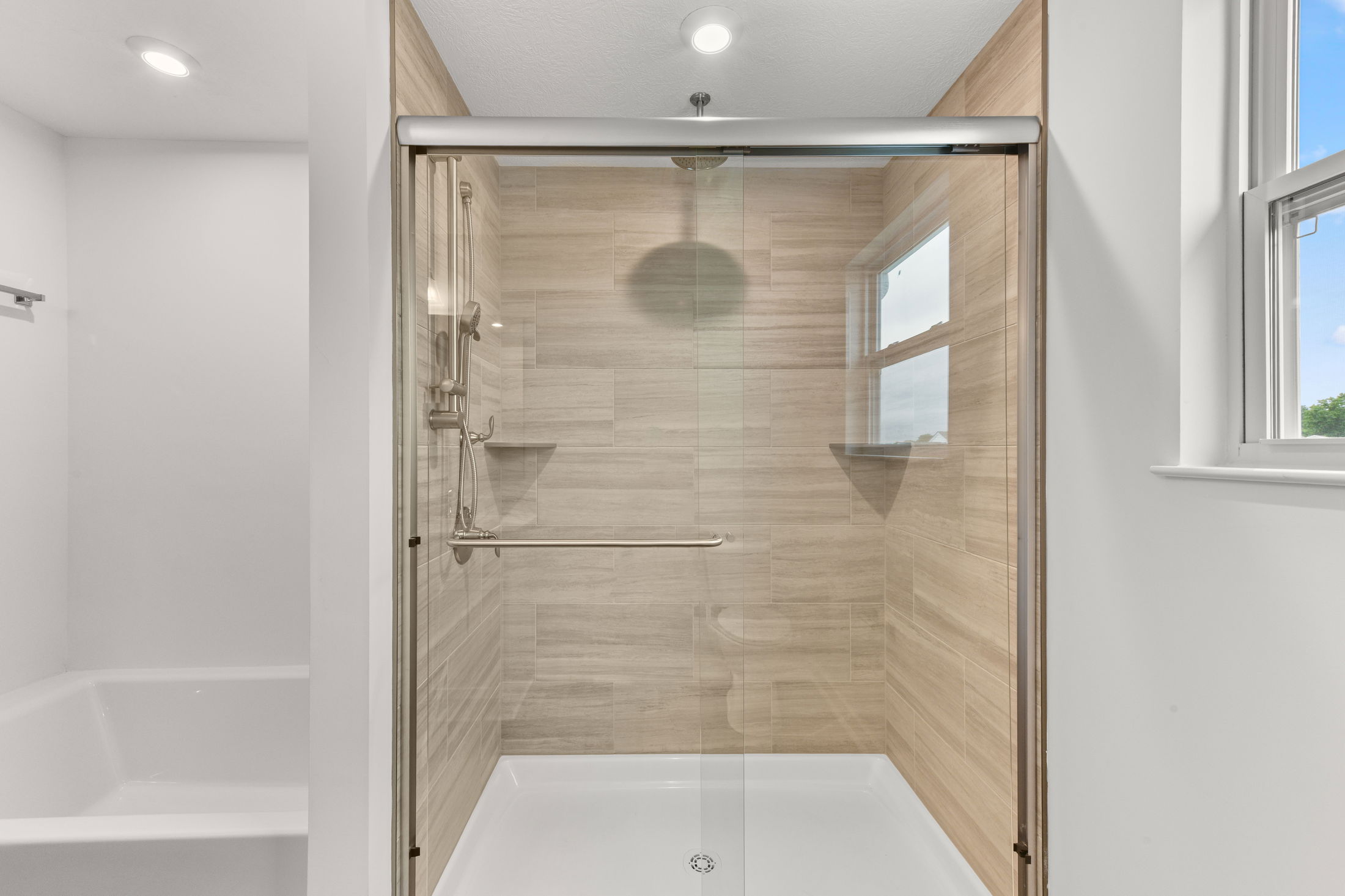 Modern bathroom featuring a glass-enclosed shower with tiled walls and a built-in window.