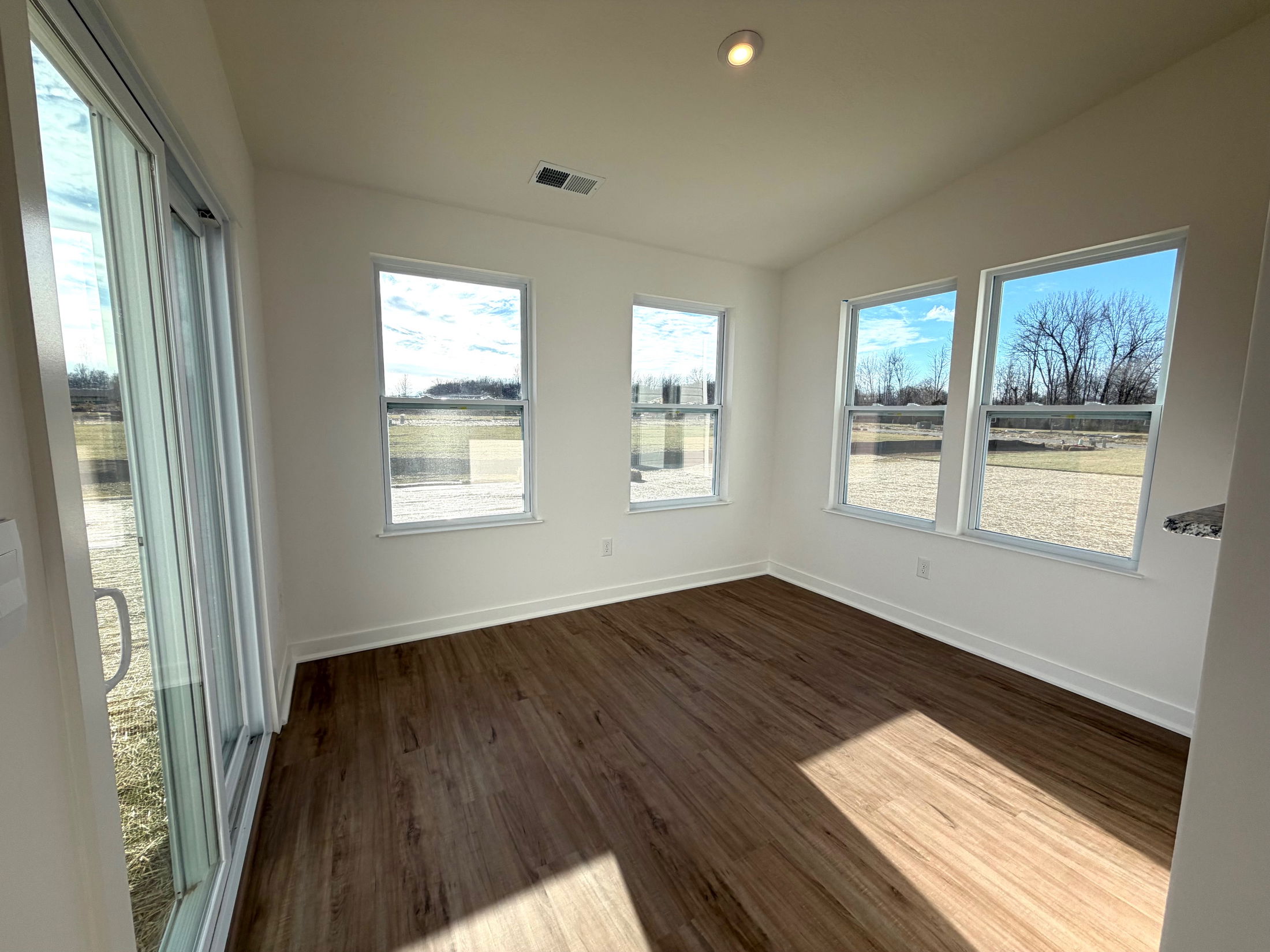 Bright and airy sunroom featuring large windows, natural light, and wood flooring.