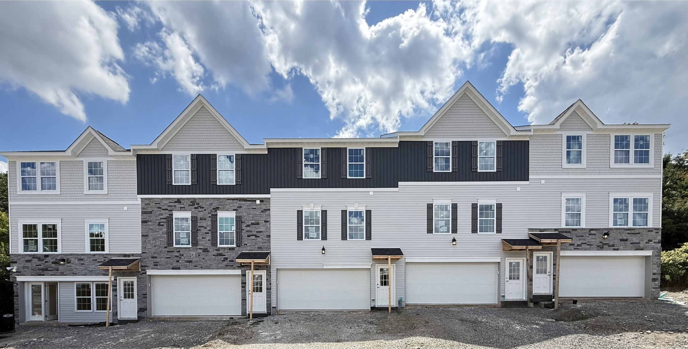 Newly constructed townhouse complex with modern architecture under a blue sky.