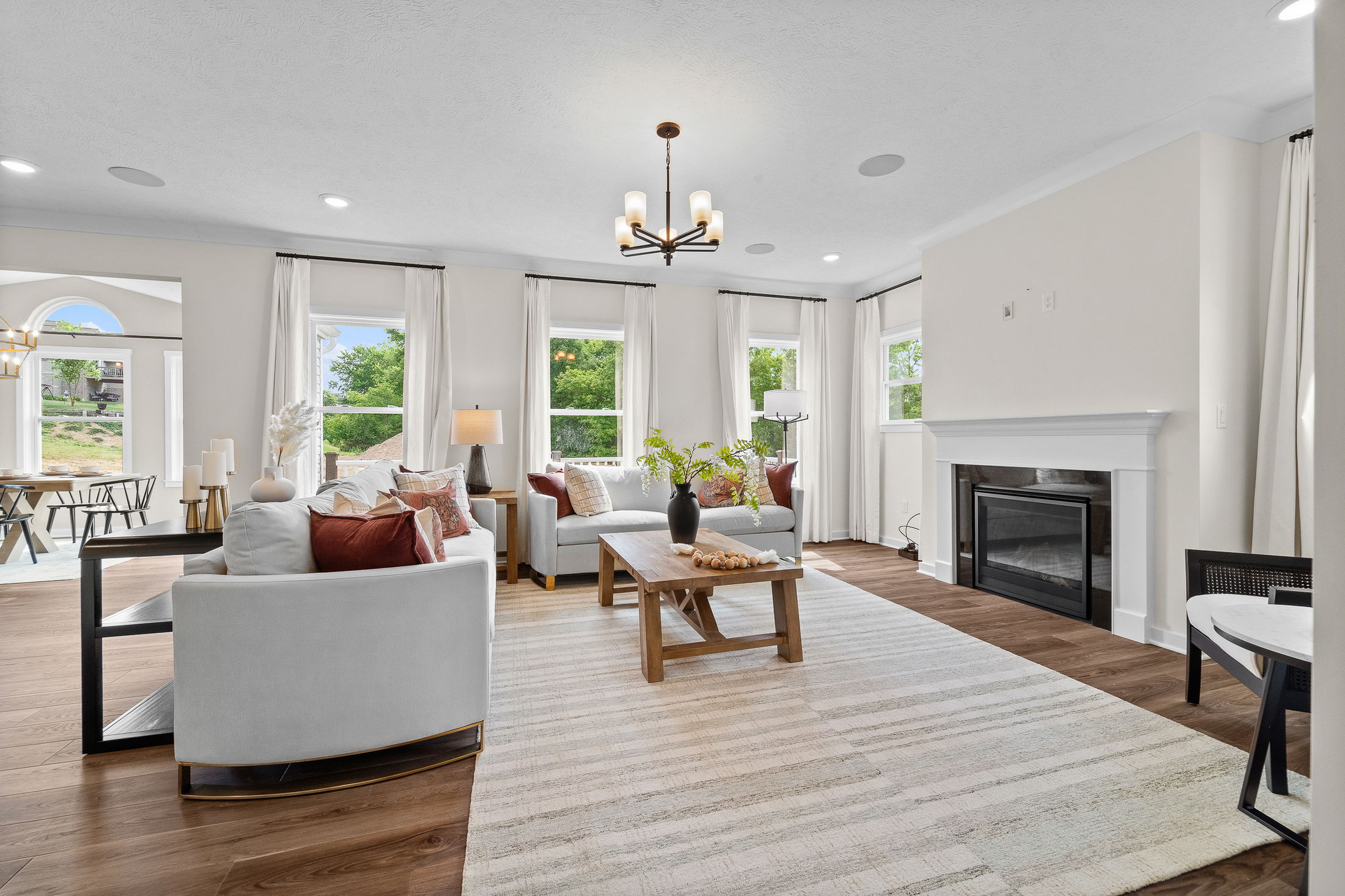 Bright and airy modern living room with elegant furnishings, a cozy fireplace, and large windows offering natural light.