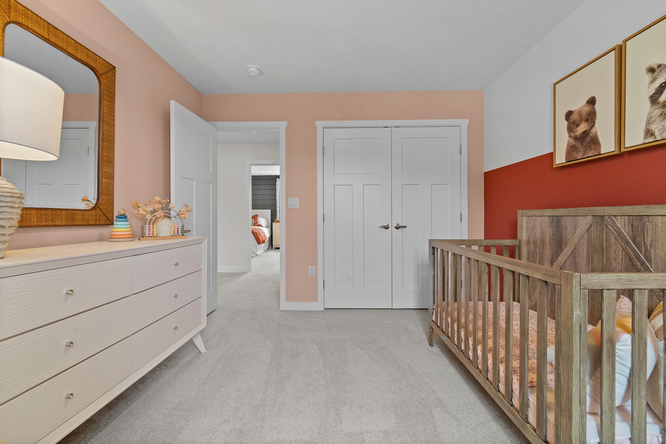 Modern nursery room with a wooden crib, white dresser, and colorful wall art.