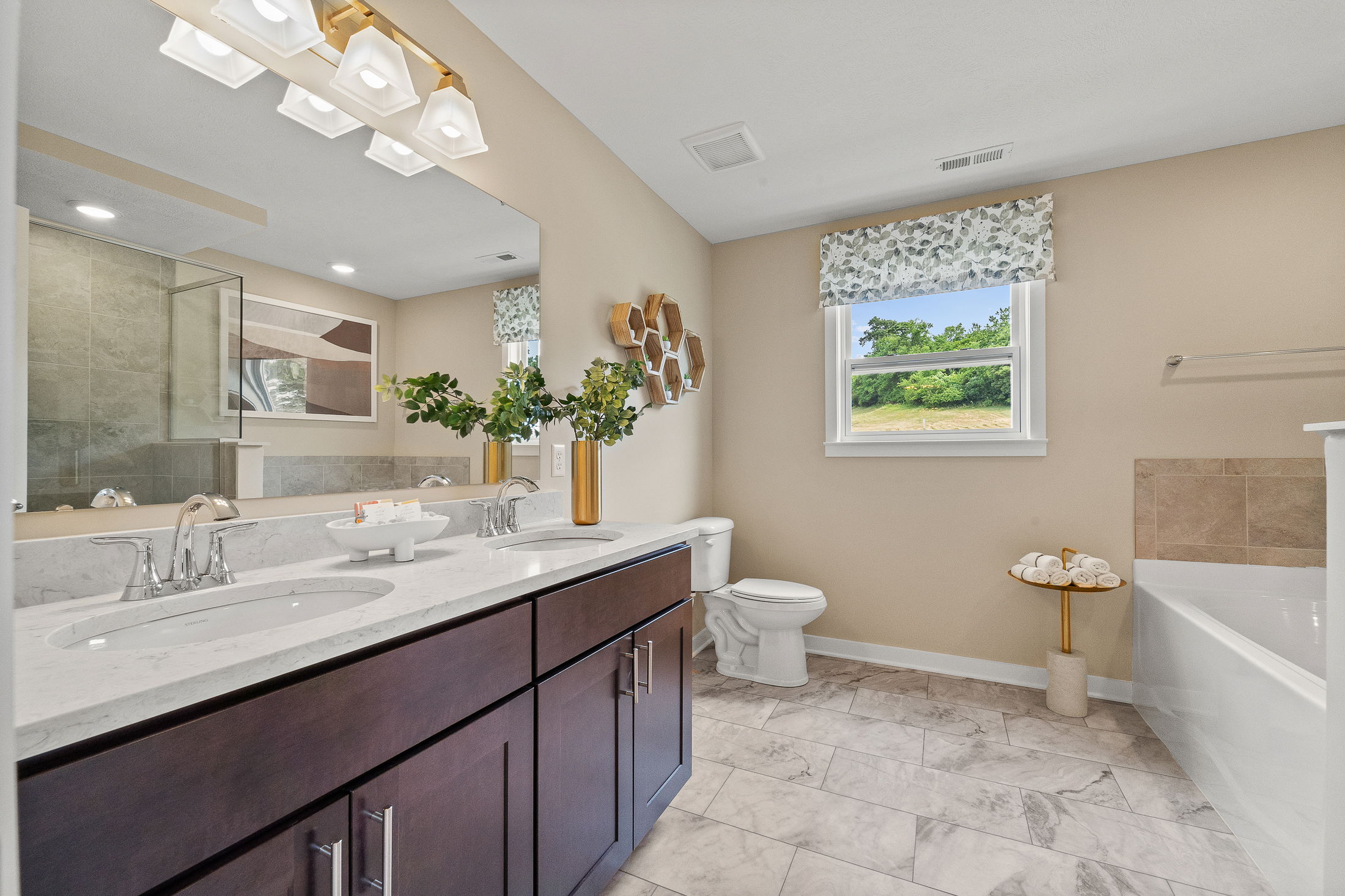 Modern bathroom featuring a double sink vanity with marble countertop, contemporary lighting, and scenic window view.