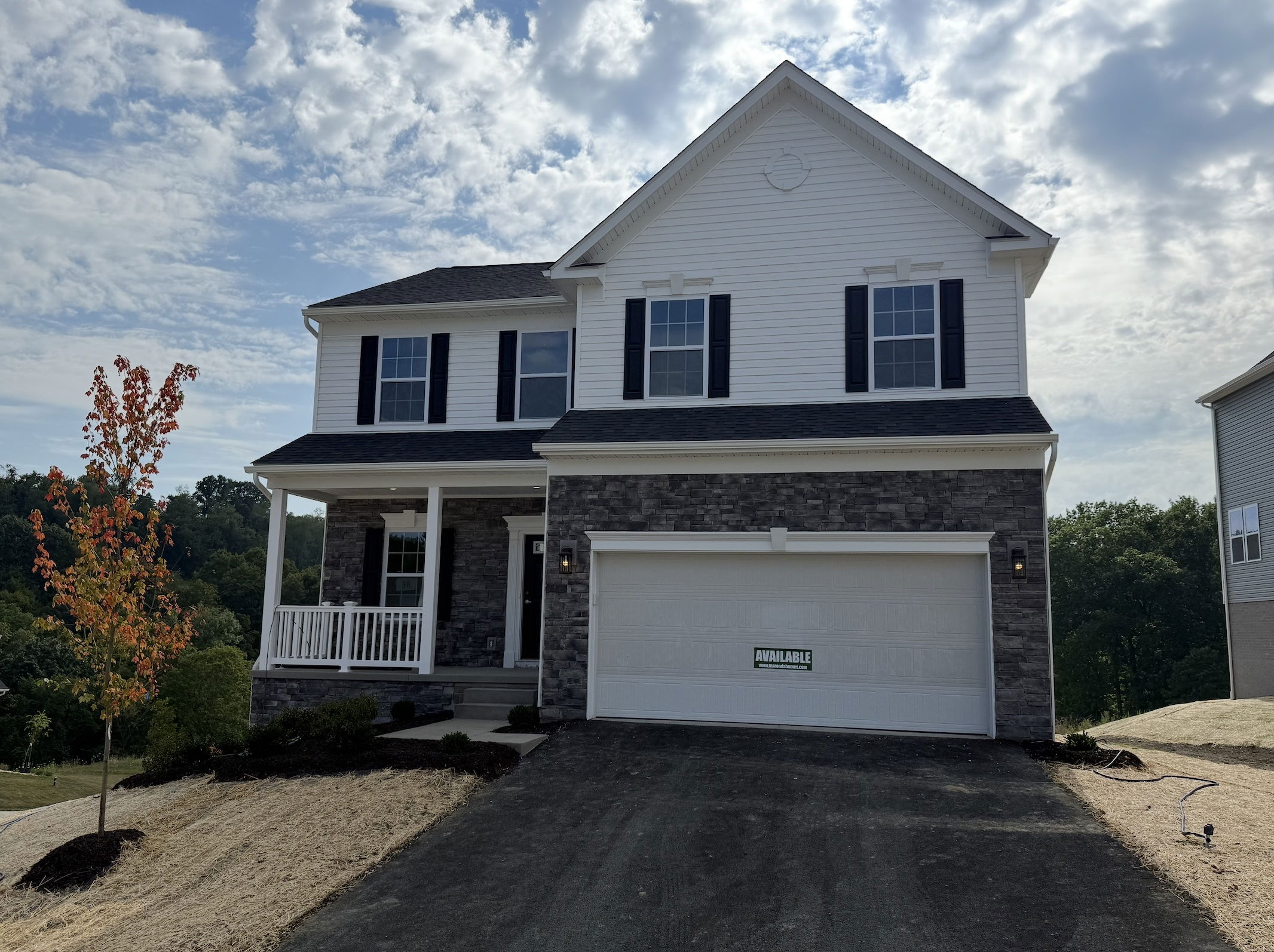 Newly constructed two-story house with a brick facade and attached garage for sale under a cloudy sky.