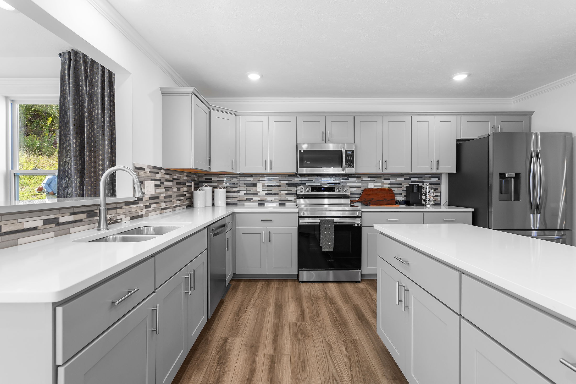Modern kitchen with sleek gray cabinets, stainless steel appliances, and a stylish backsplash.