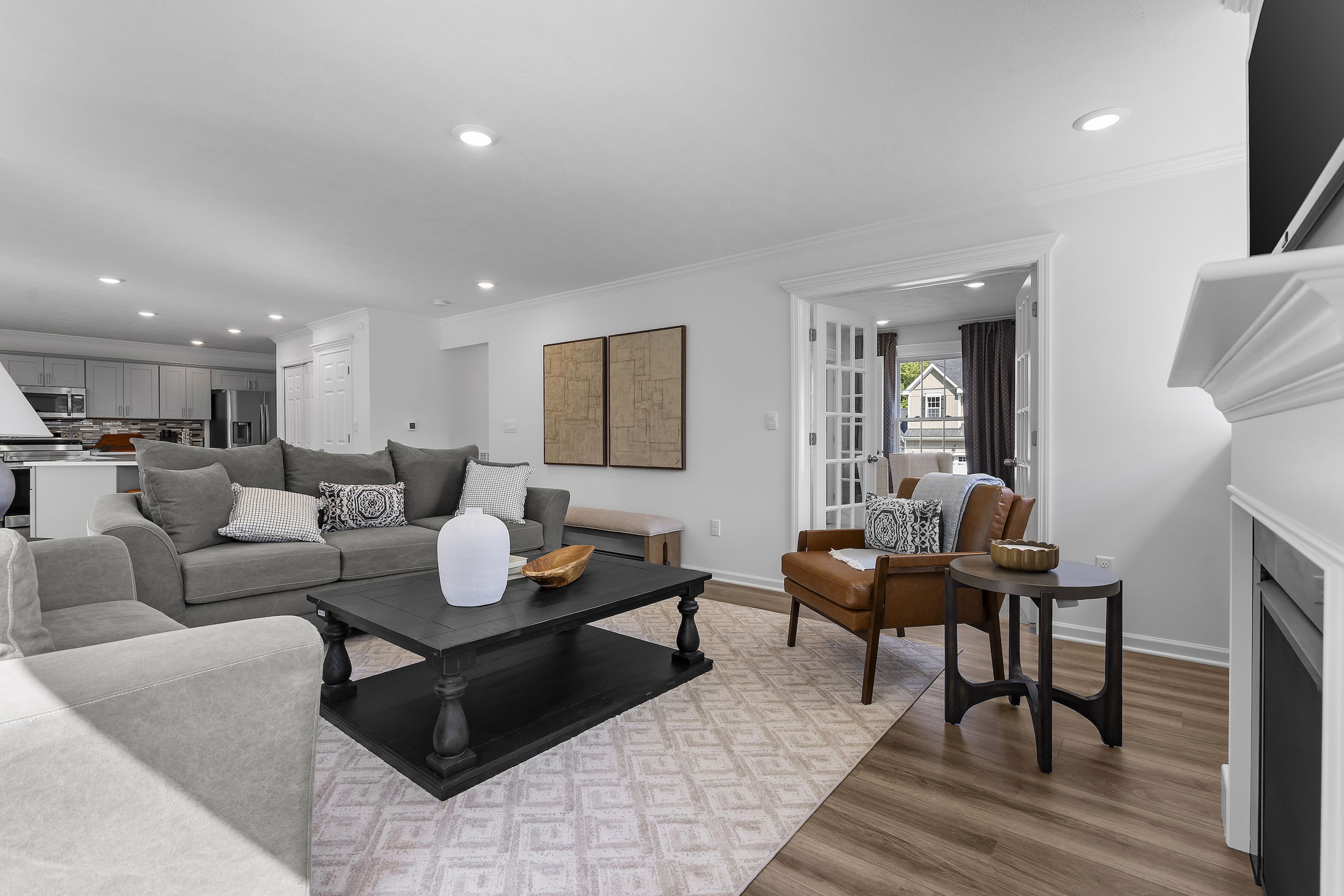 Modern living room with gray sofa, black coffee table, and open concept view into a stylish kitchen.