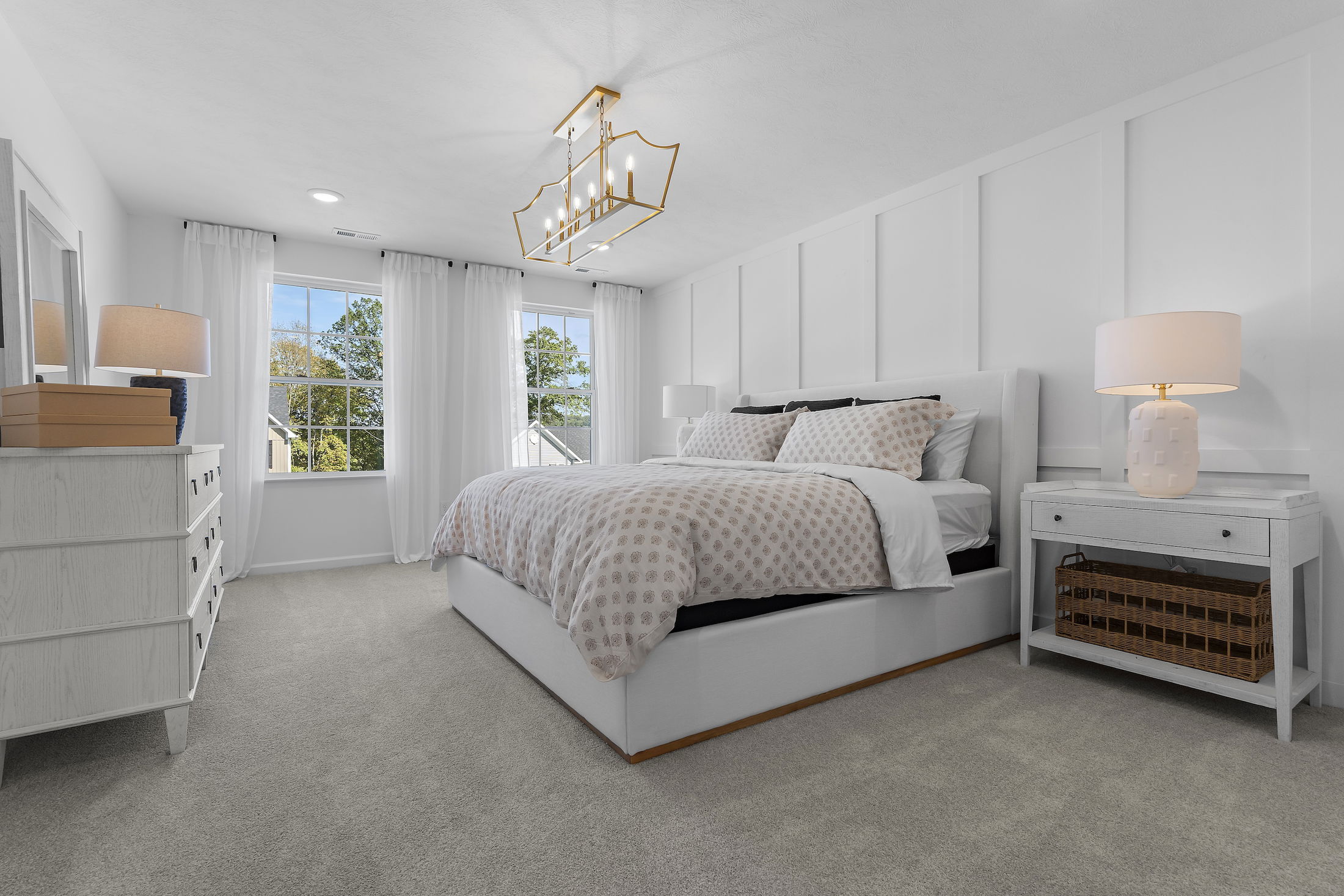 Bright, modern bedroom with a large bed, elegant pendant light, and white furnishings.