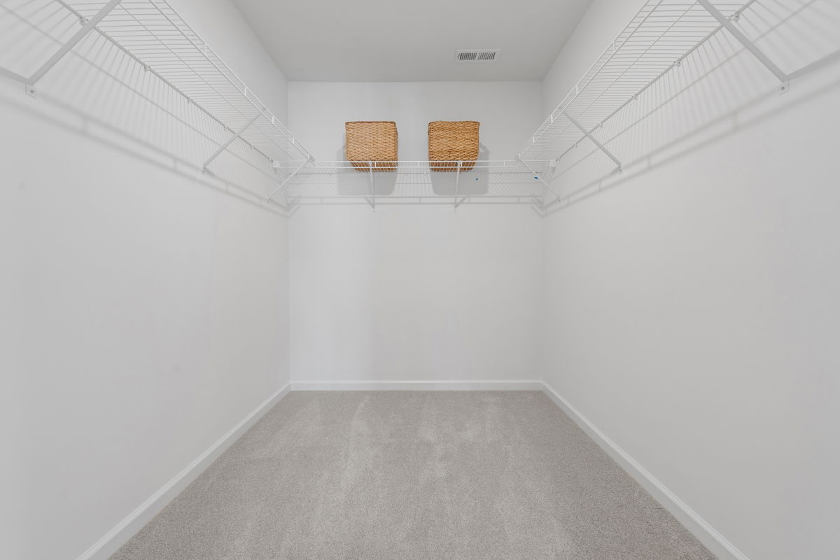 Spacious empty walk-in closet with white wire shelving and two wicker baskets, perfect for organized storage.