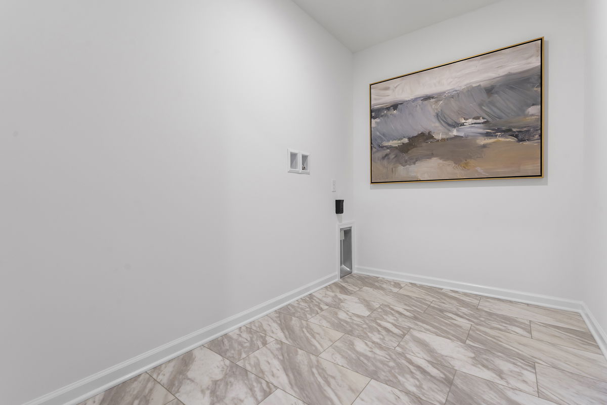 Minimalist laundry room with abstract artwork and marble tile flooring.