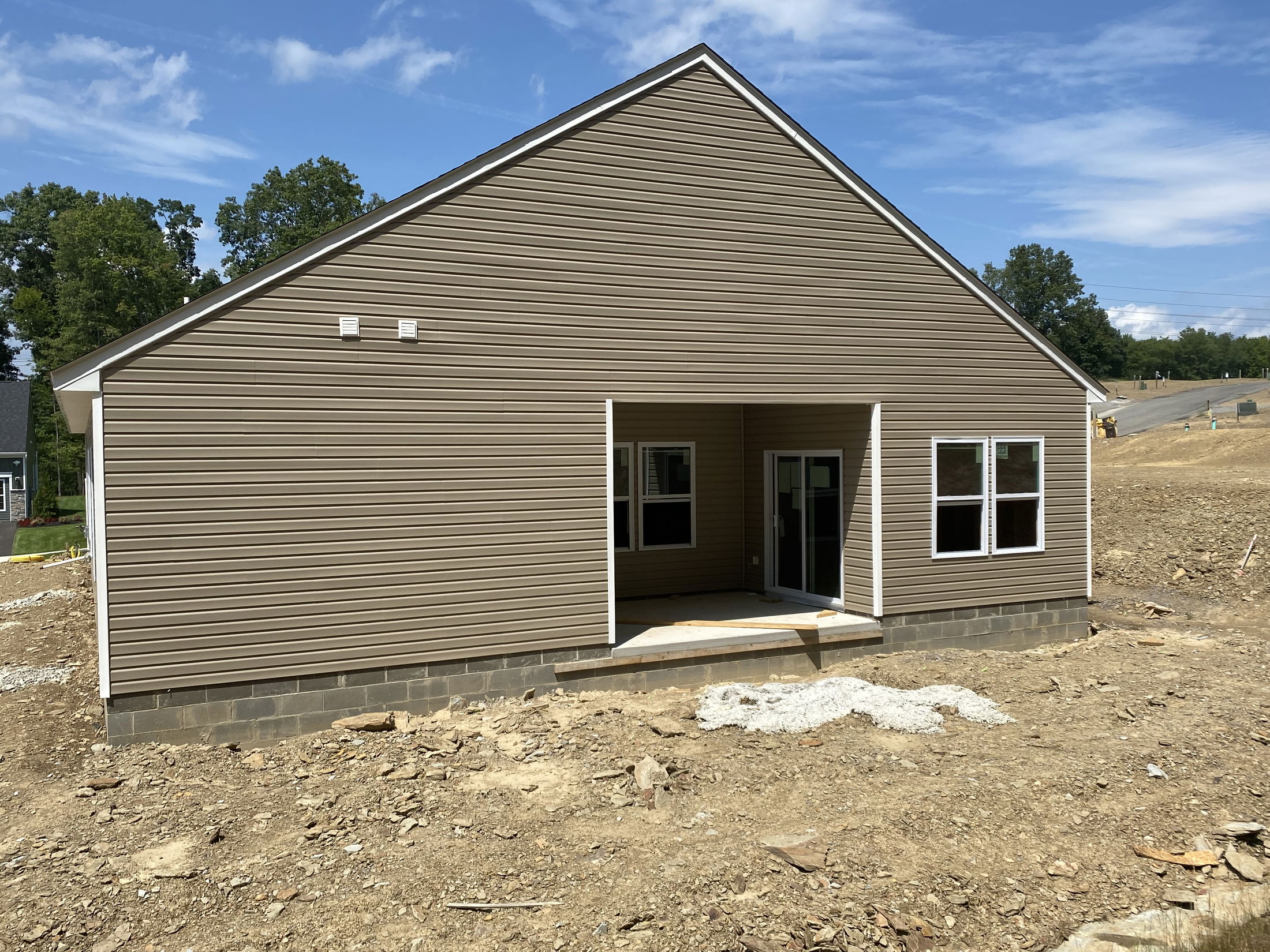 Newly constructed house with brown siding and a small porch under a clear blue sky.