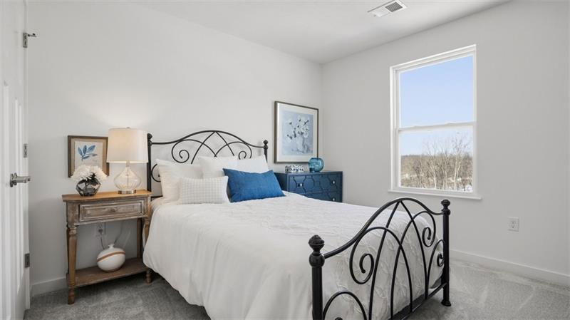 Cozy and modern bedroom featuring a black iron bed, blue accents, and natural light from a window.