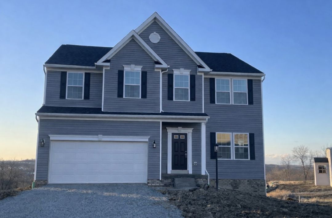 Modern two-story gray house with black shutters and a two-car garage against a clear blue sky.