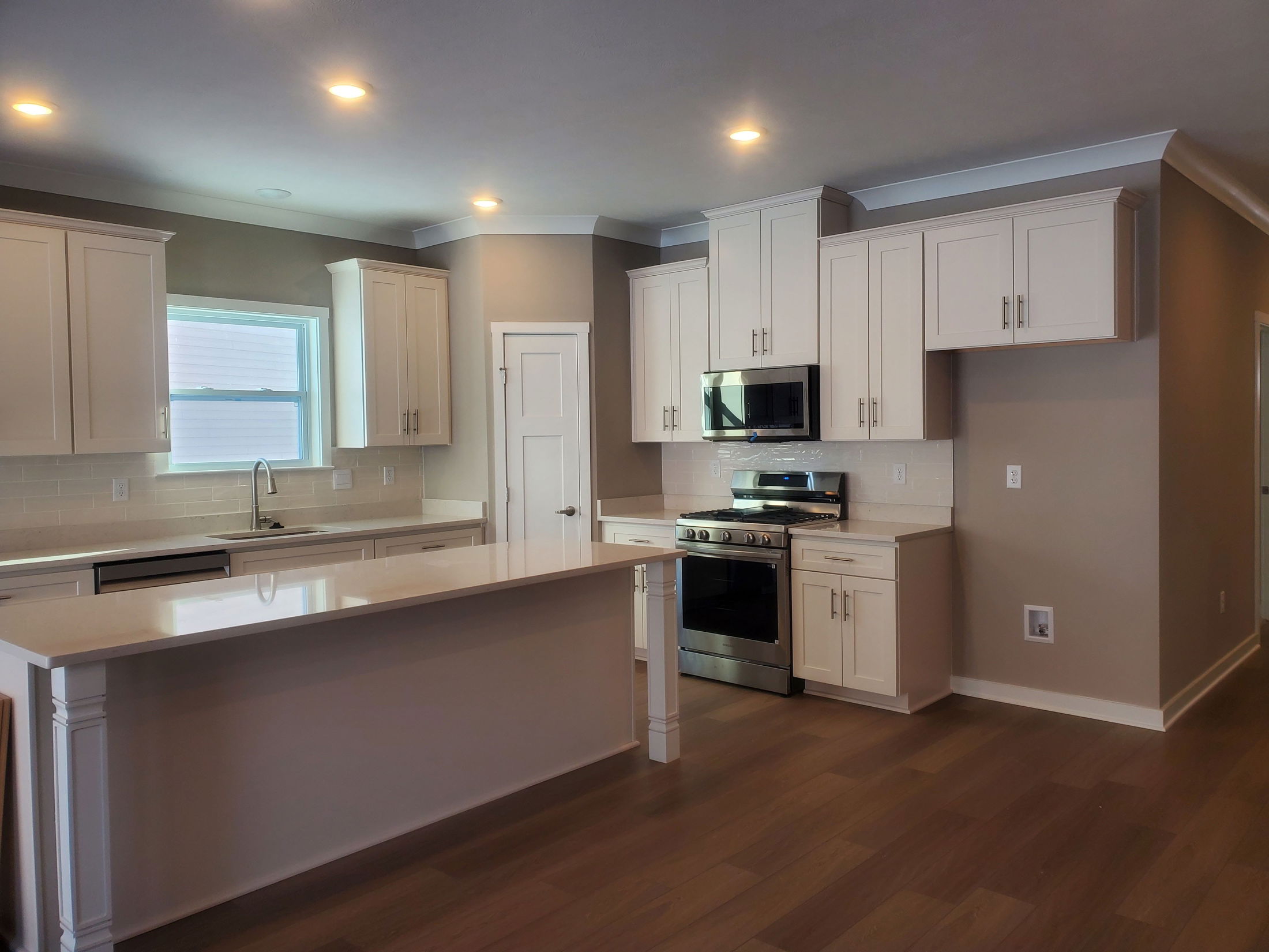 Modern kitchen interior featuring white cabinetry, stainless steel appliances, and hardwood flooring.