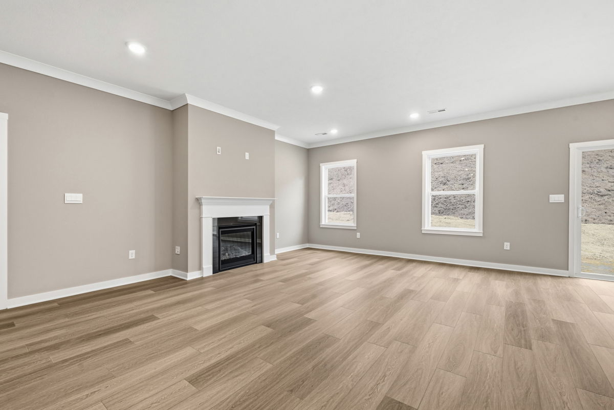Spacious living room with a modern fireplace and large windows featuring light wood flooring and neutral wall colors.
