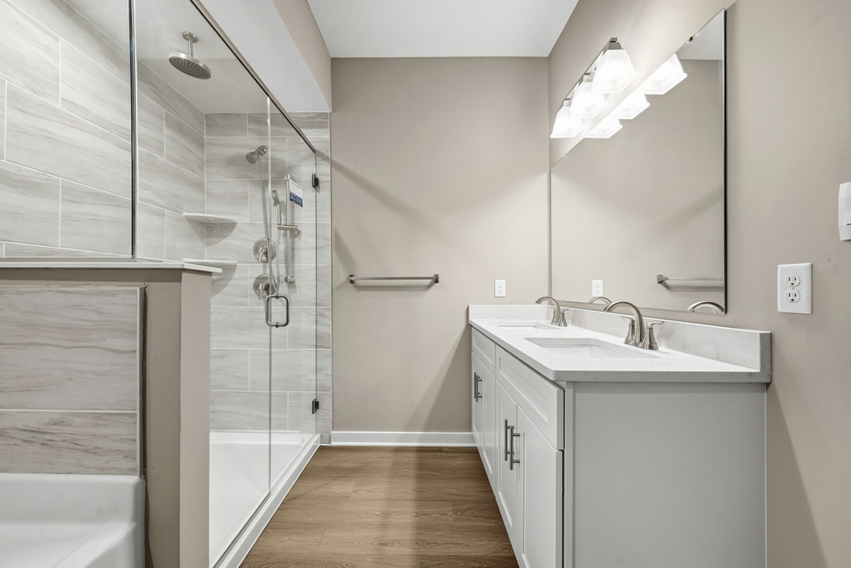 Modern bathroom interior featuring a glass shower enclosure, dual sinks, and elegant light fixtures.