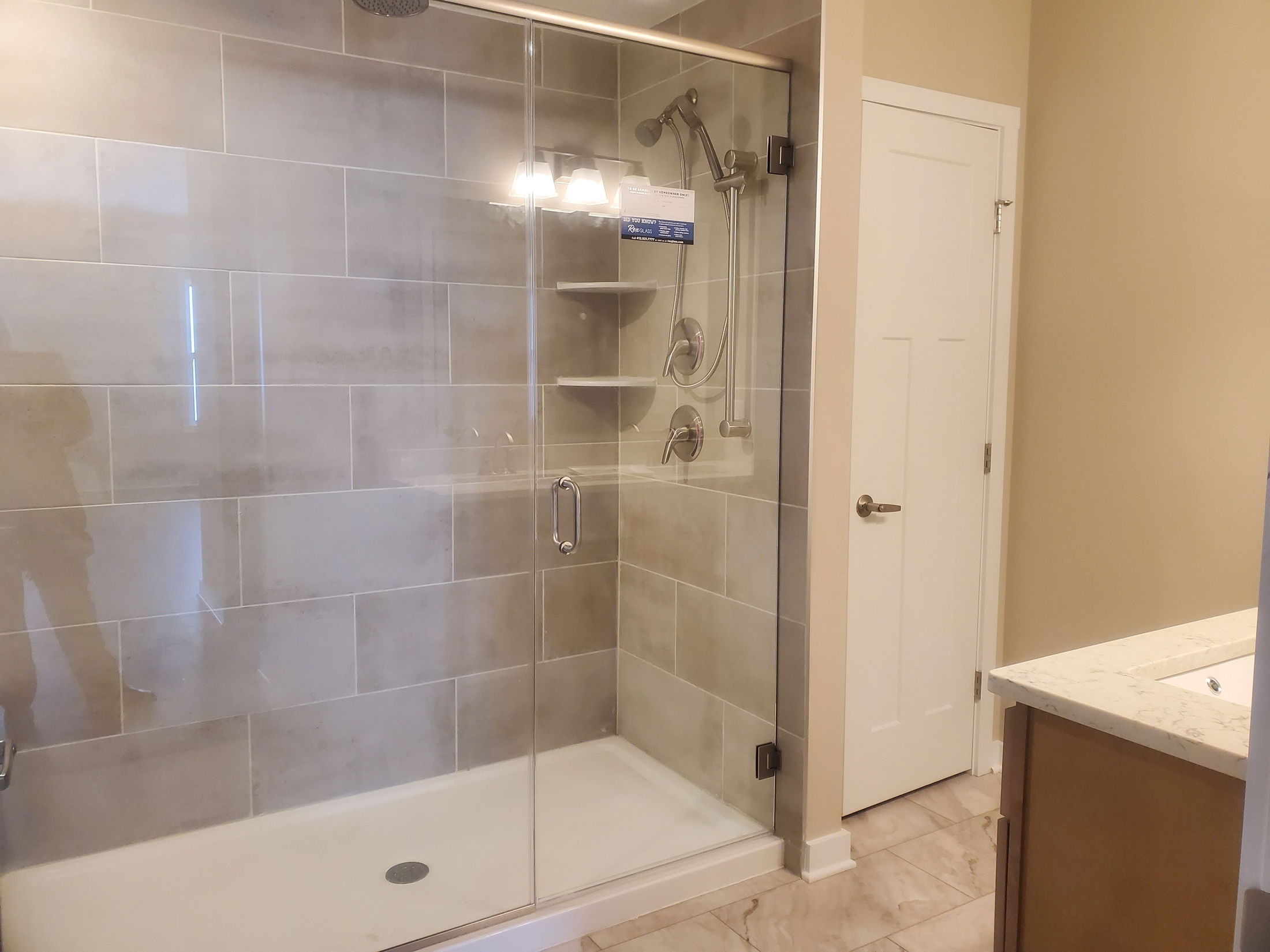 Modern bathroom featuring a glass-enclosed walk-in shower with neutral tile and a sleek countertop.