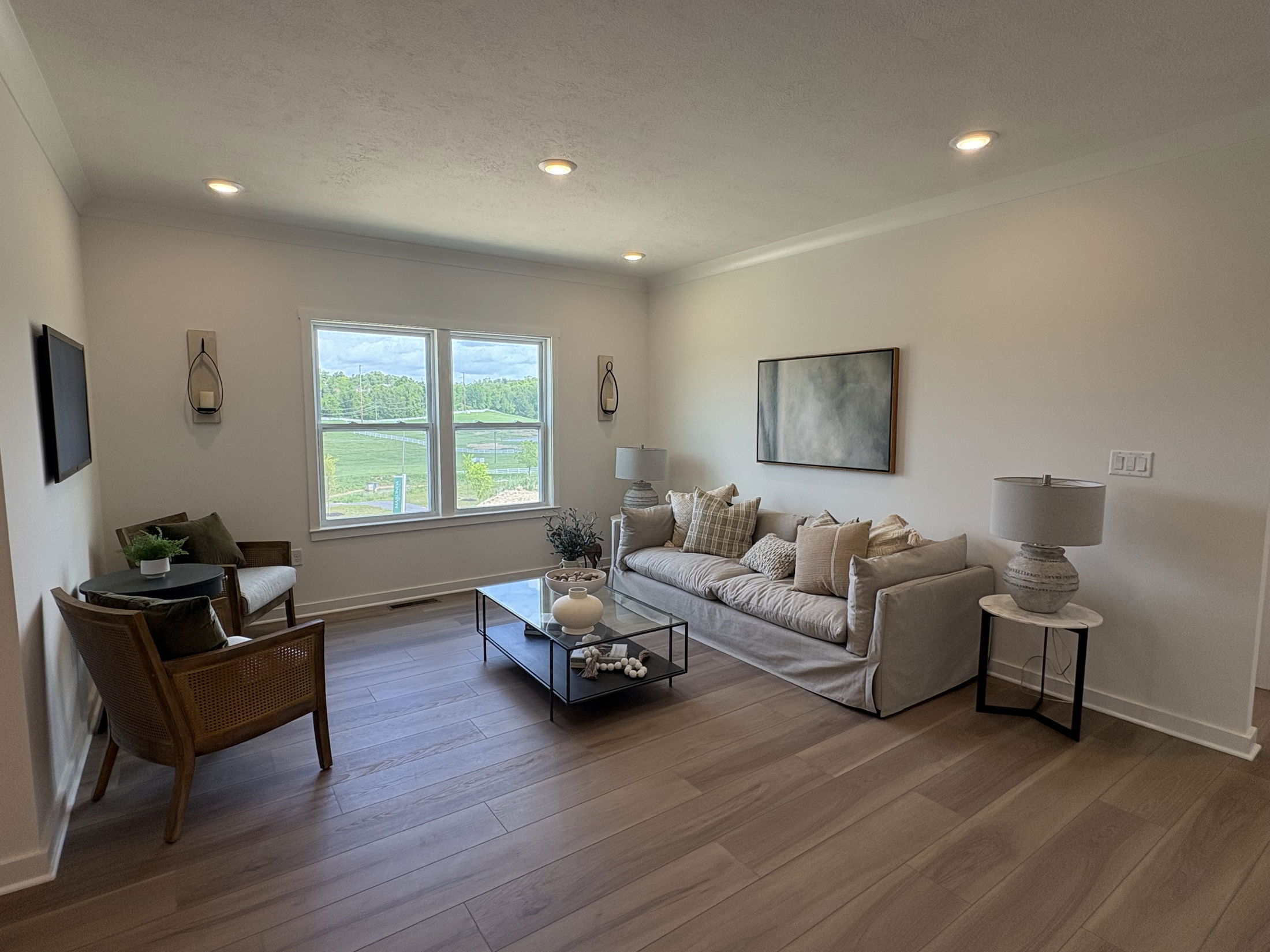 Modern living room with a neutral color scheme, featuring a comfortable sofa, wooden chairs, decorative pillows, large window, and minimalist decor.