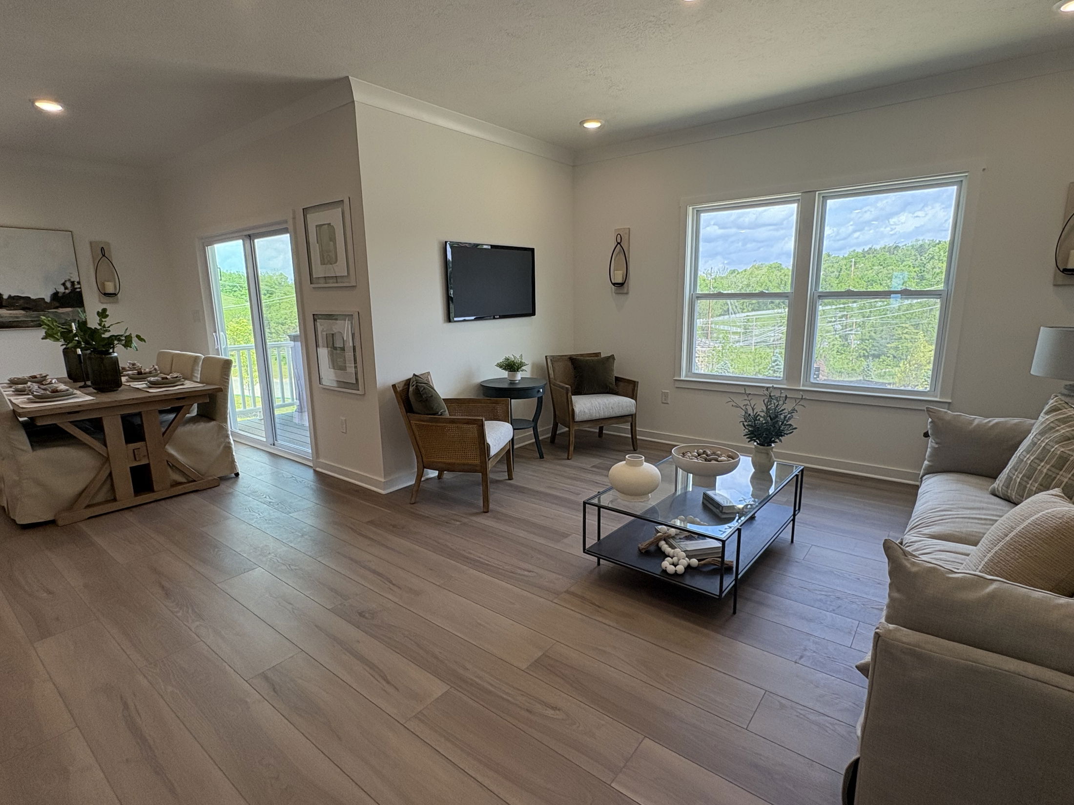 Modern living room with wooden flooring, stylish decor, and large windows showcasing a scenic outdoor view.
