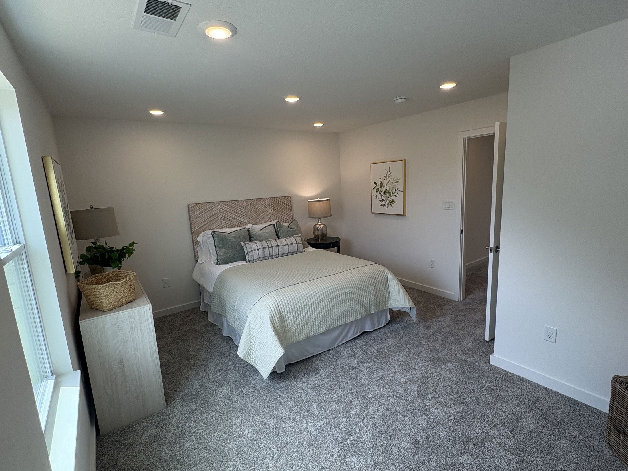 Elegant modern bedroom with cozy carpet flooring, neutral walls, and ambient lighting.