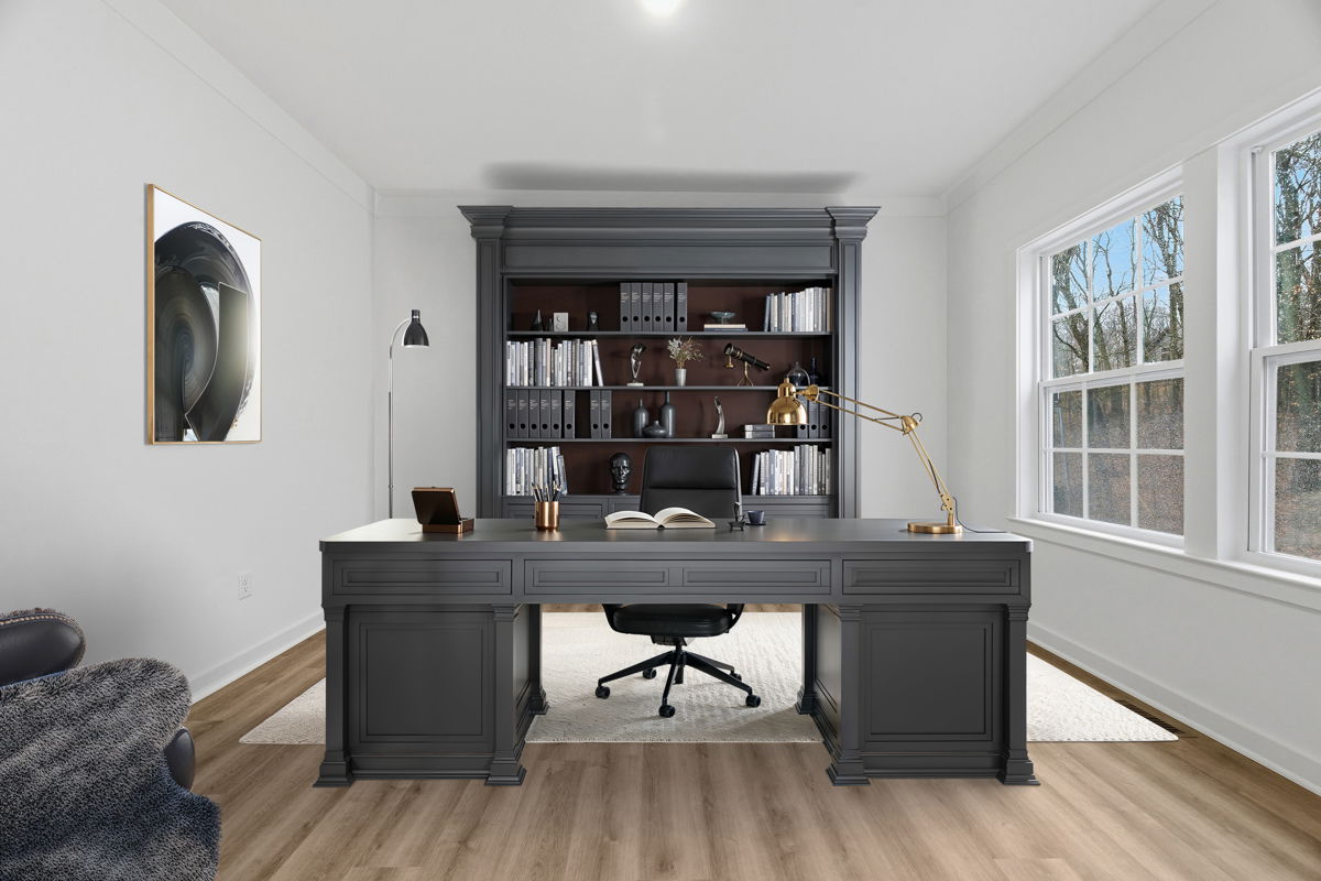 Modern home office with a large gray desk, stylish bookshelves, and natural light from big windows.