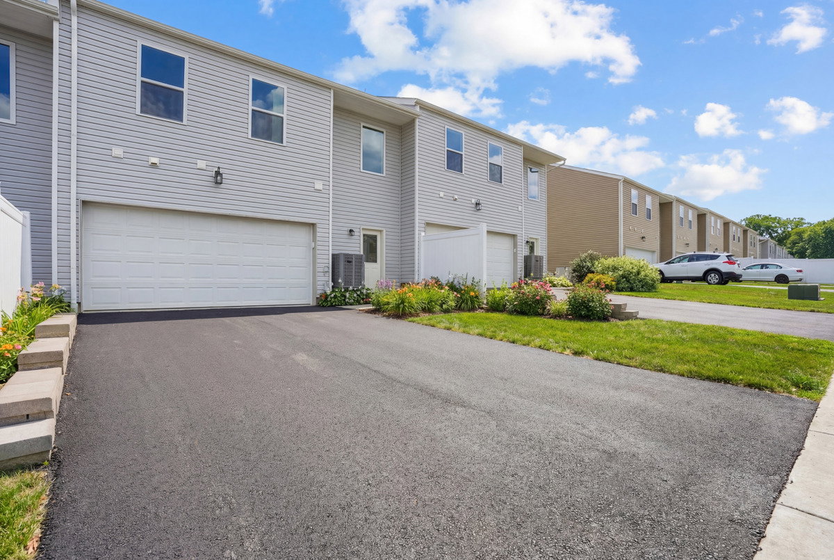 Residential buildings with garages and landscaped front yards on a sunny day.