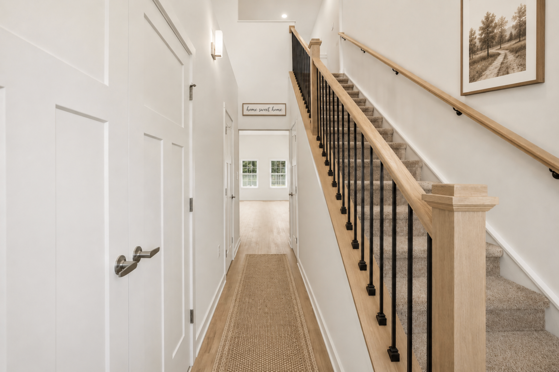 A hallway featuring a staircase, light-colored walls, and a carpet runner leading to an open space with large windows.
