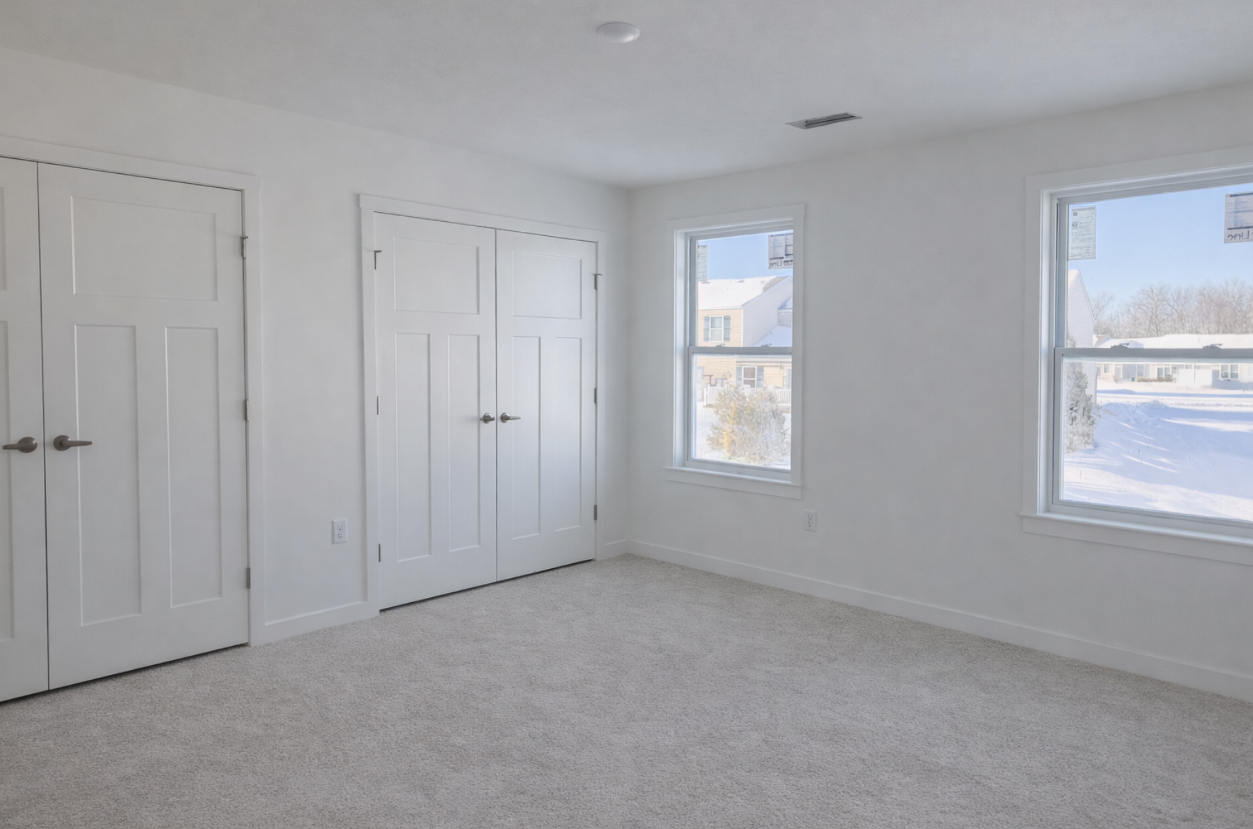 Bright and airy modern bedroom featuring large windows, plush carpet, and double closet doors.