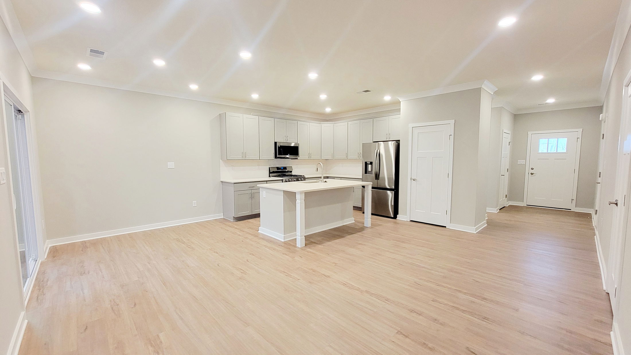 Modern open-concept kitchen with white cabinetry, hardwood floors, and stainless steel appliances.