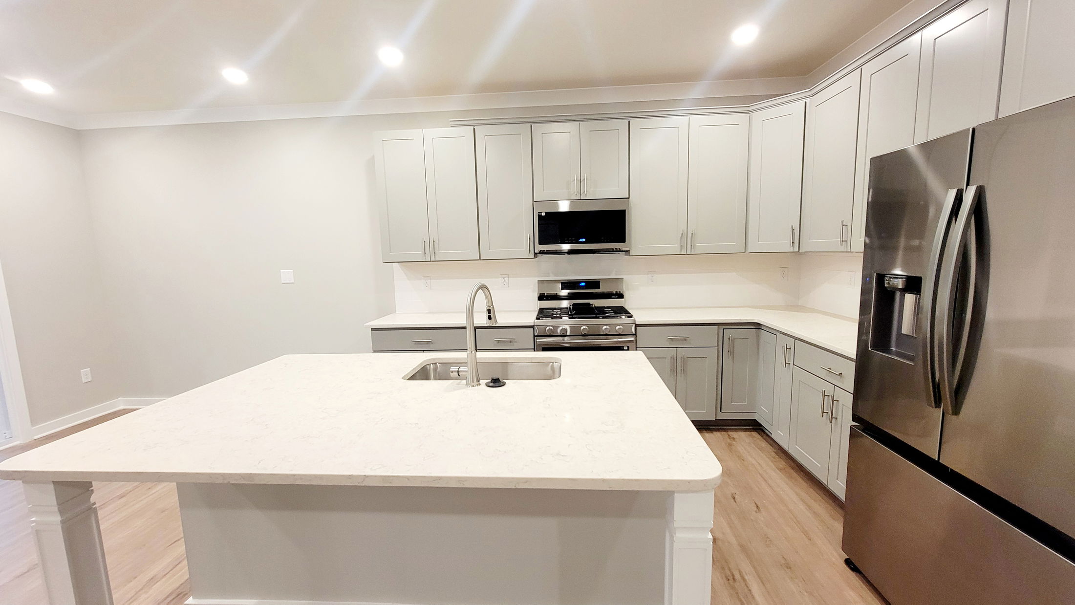 Modern kitchen with white countertops, stainless steel appliances, and light gray cabinets.