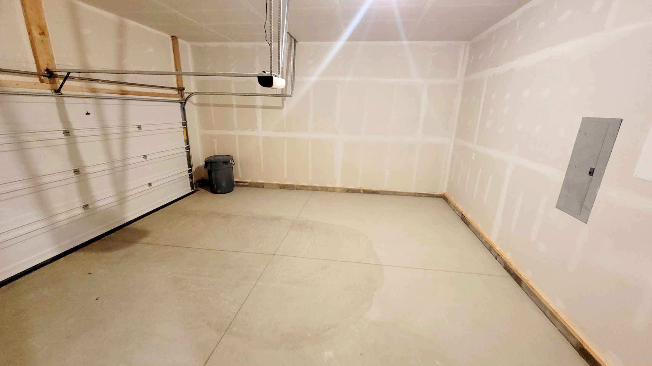 Empty garage interior with white drywall, concrete floor, and a closed sectional garage door.