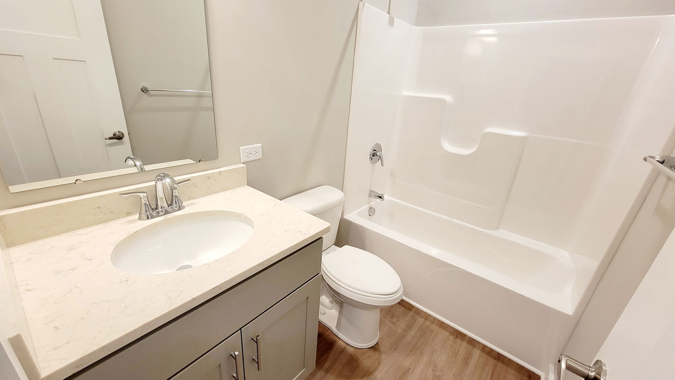Modern bathroom with a sleek white vanity, integrated sink, and bathtub surrounded by light-colored walls.