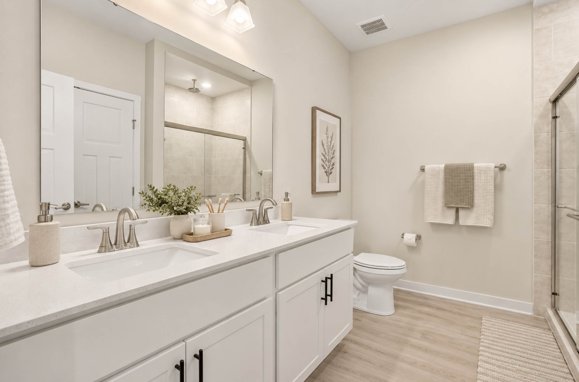 Modern bathroom featuring dual sinks, a glass shower, and neutral decor.