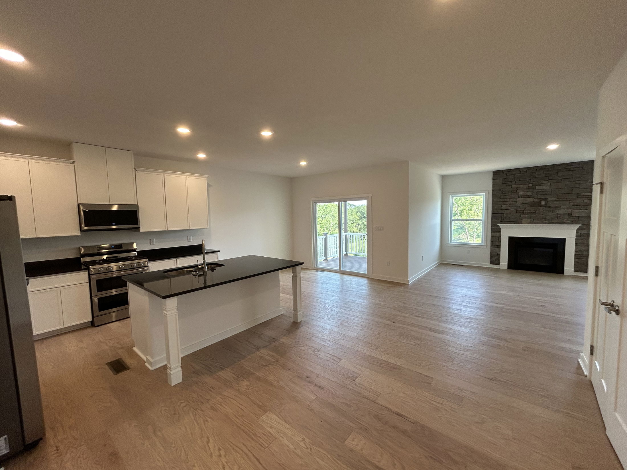 Spacious open-concept kitchen and living room with hardwood floors, sleek white cabinets, and a modern fireplace.