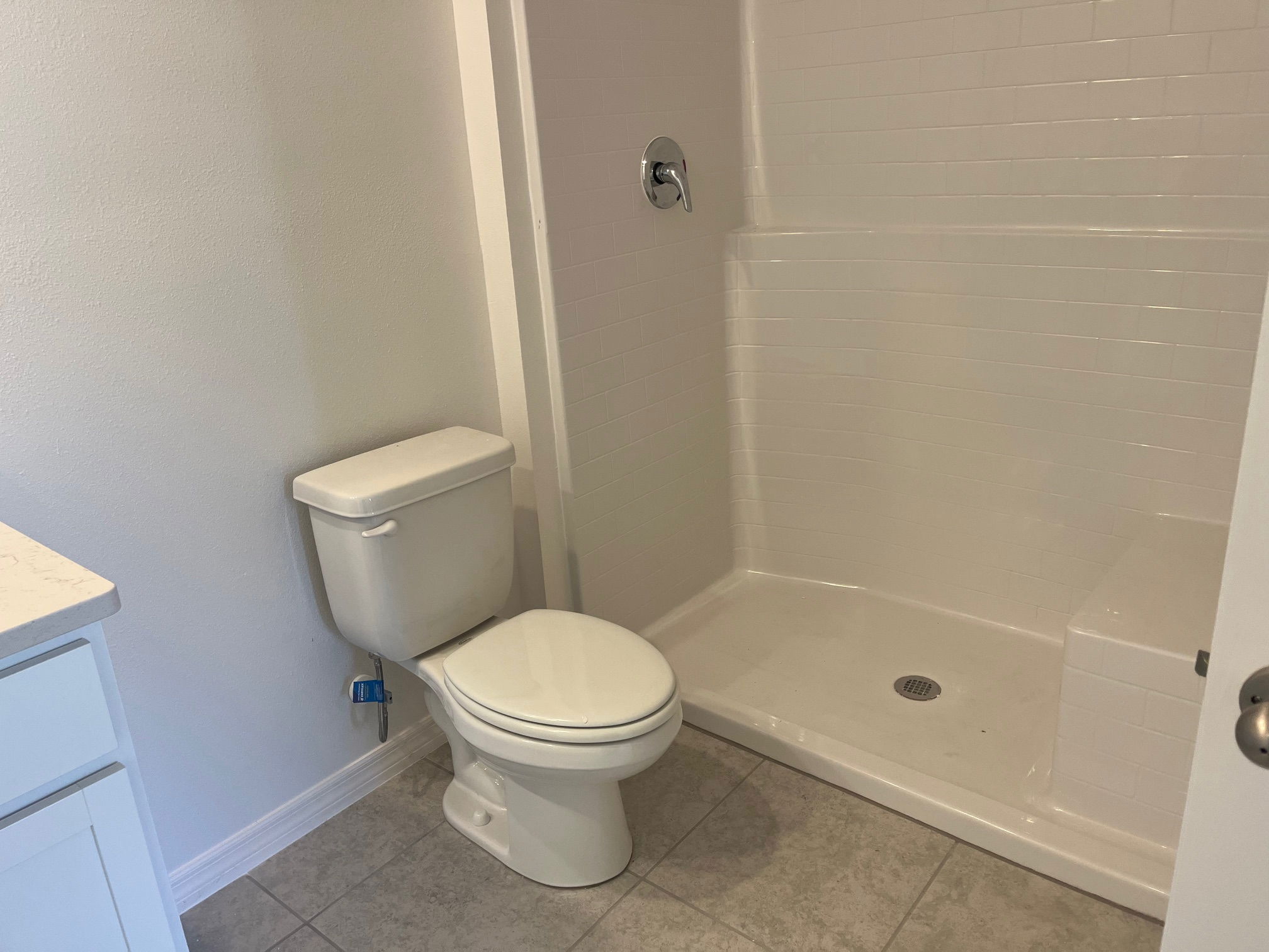 Clean, modern bathroom with a white toilet and a tiled corner shower.