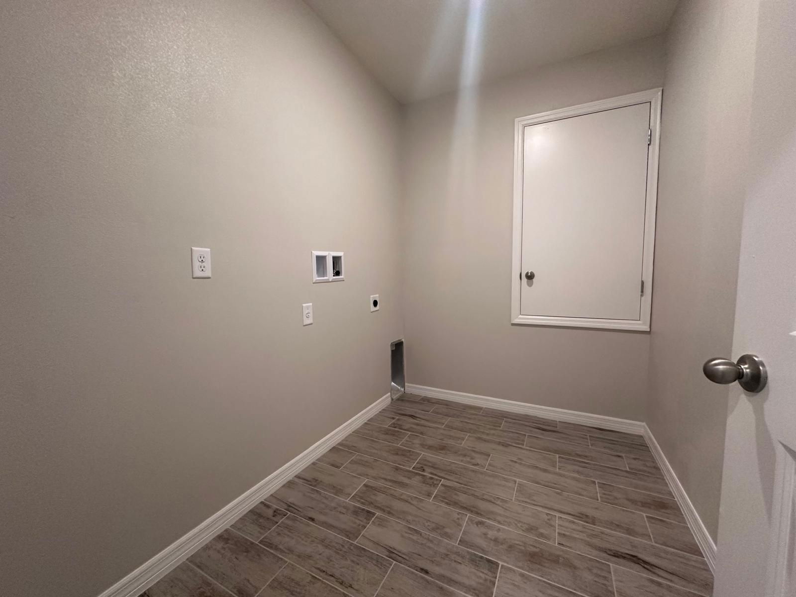Empty laundry room with beige walls, tile flooring, and hookups for a washer and dryer.