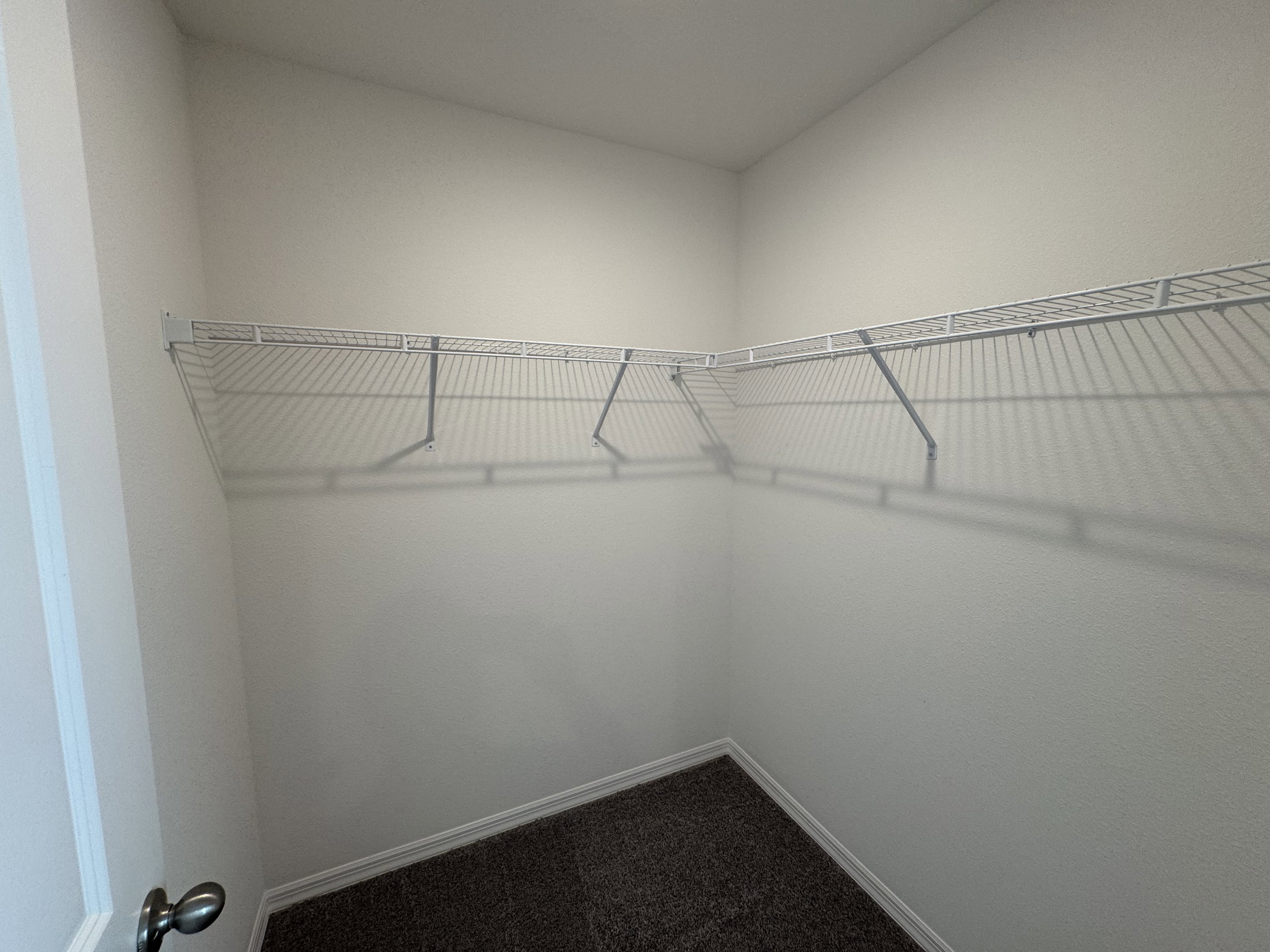 Empty closet with wire shelving against a light-colored wall.