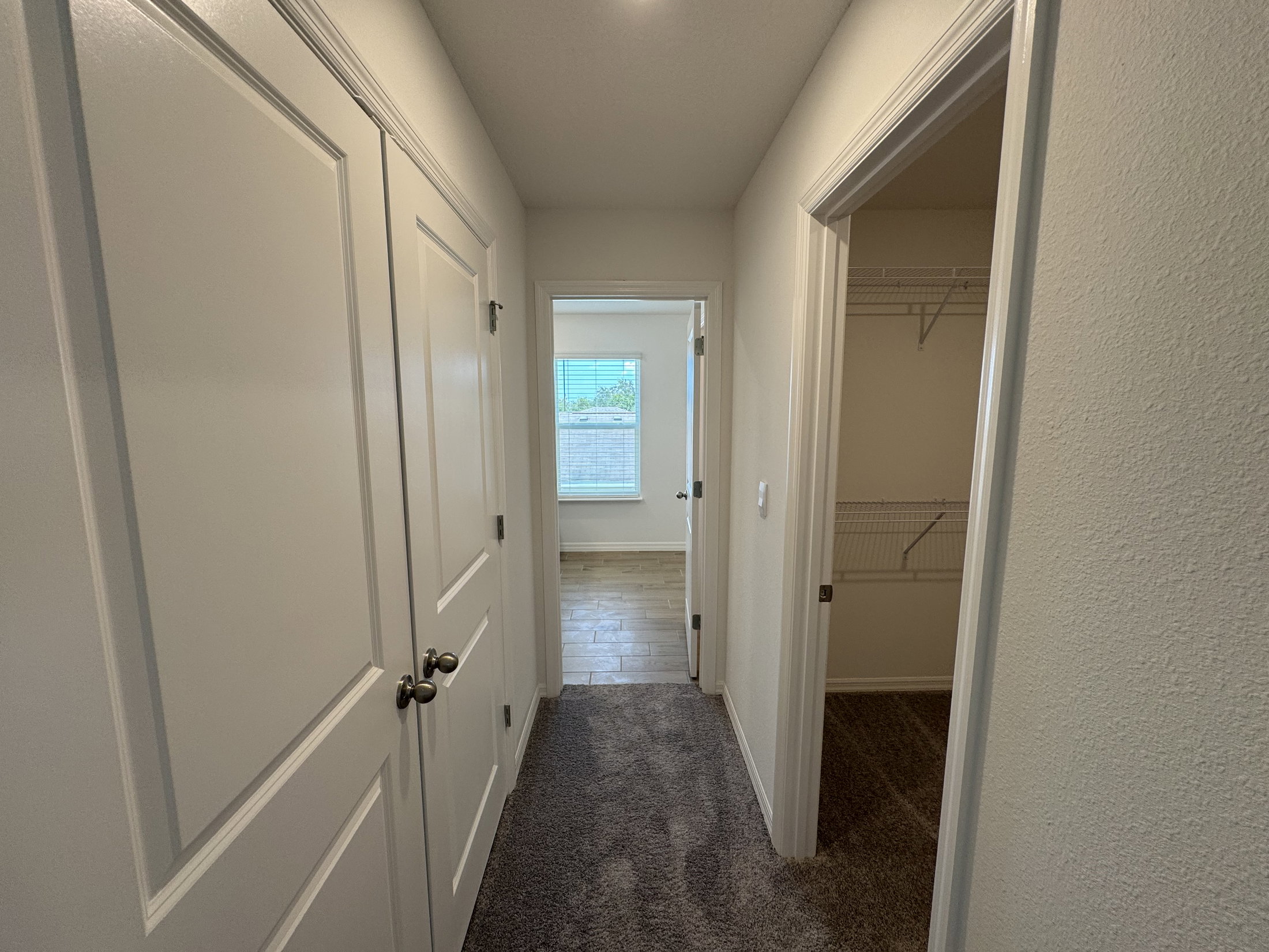 A hallway with two closed doors leading to a room and a closet.